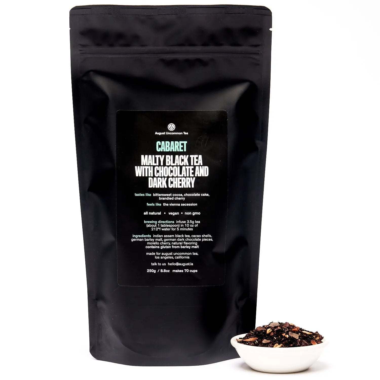 Cherry Chocolate Black Tea in a matte black resealable pouch, with a small bowl of loose black tea and fruit pieces