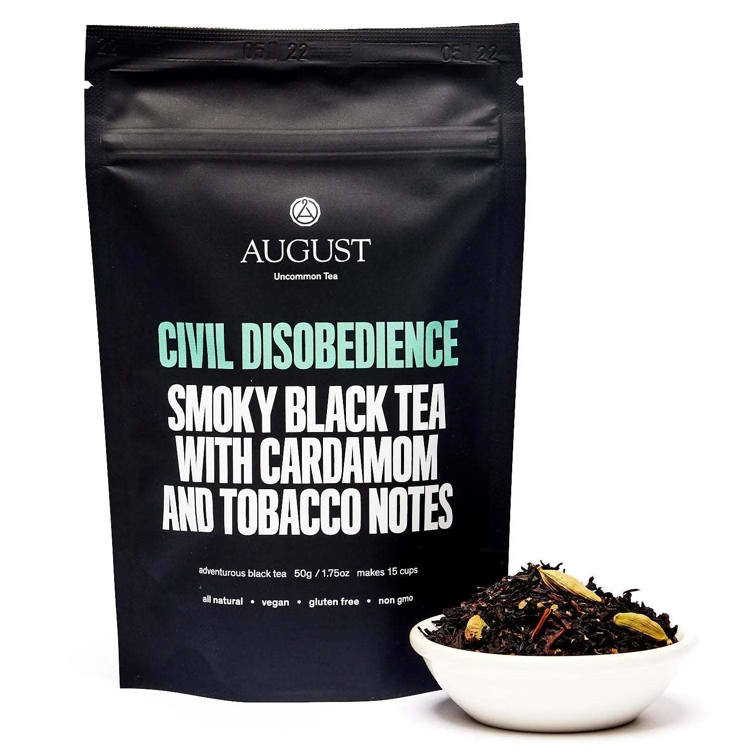 Civil Disobedience black tea pouch with bold mint and white lettering beside loose dark tea leaves and cardamom