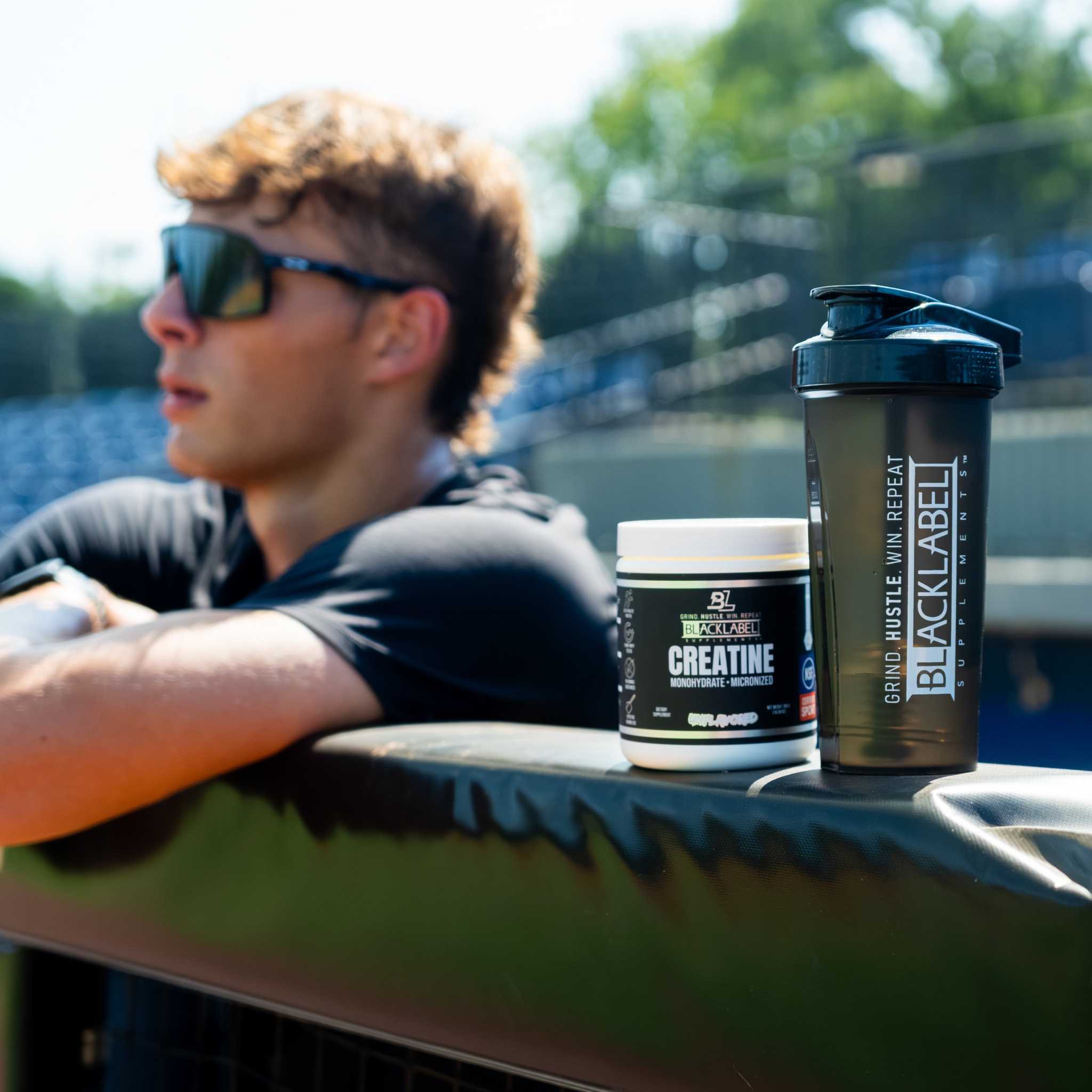 CREATINE MONOHYDRATE supplement in a black and white tub beside a black shaker bottle with bold vertical lettering