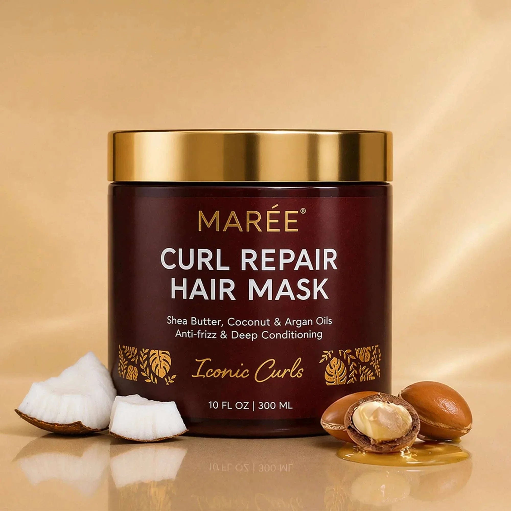 Curl Repair Hair Mask in a dark brown jar with a gold lid and gold botanical accents, shown with coconut and argan nuts
