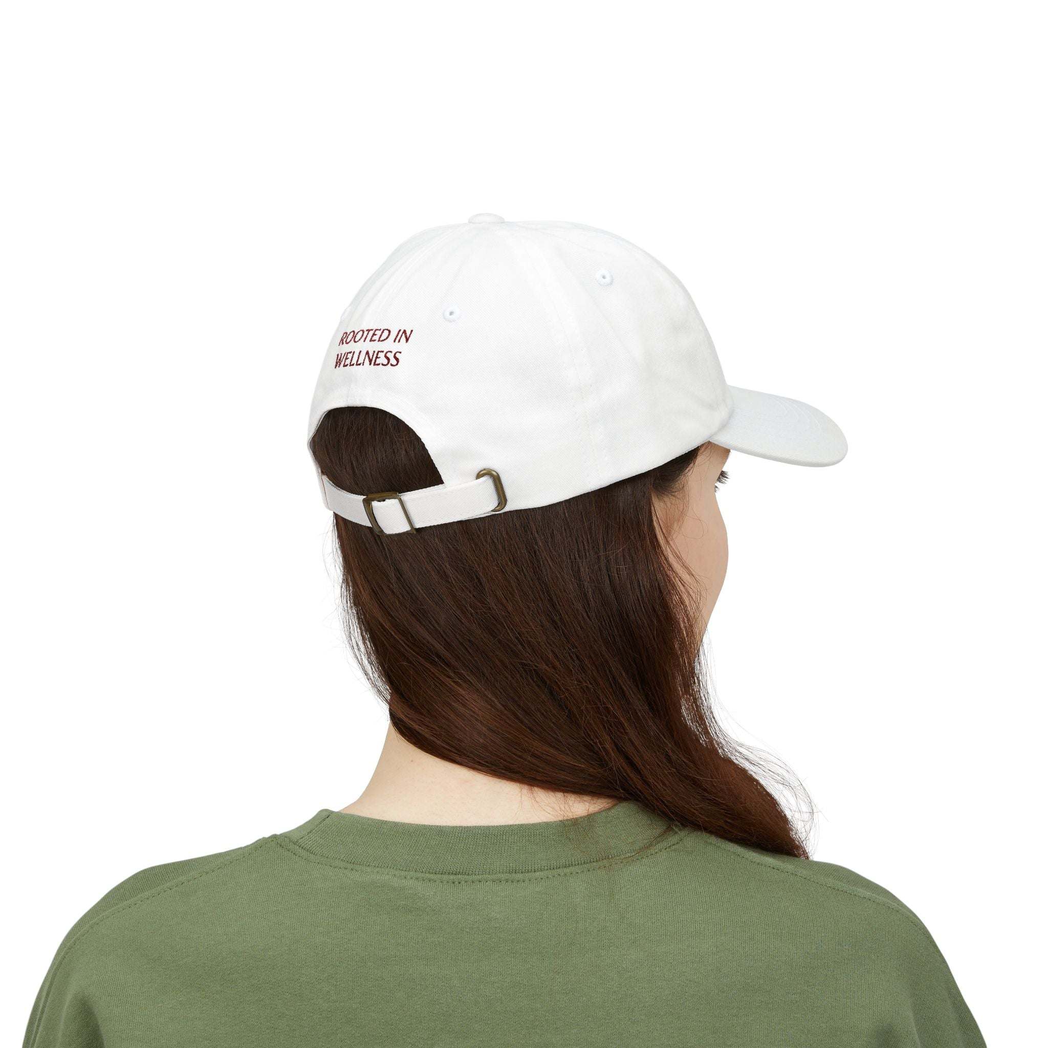 Dad Cap in white cotton with an adjustable antique brass buckle strap and embroidered "Rooted in Wellness" text on the back.