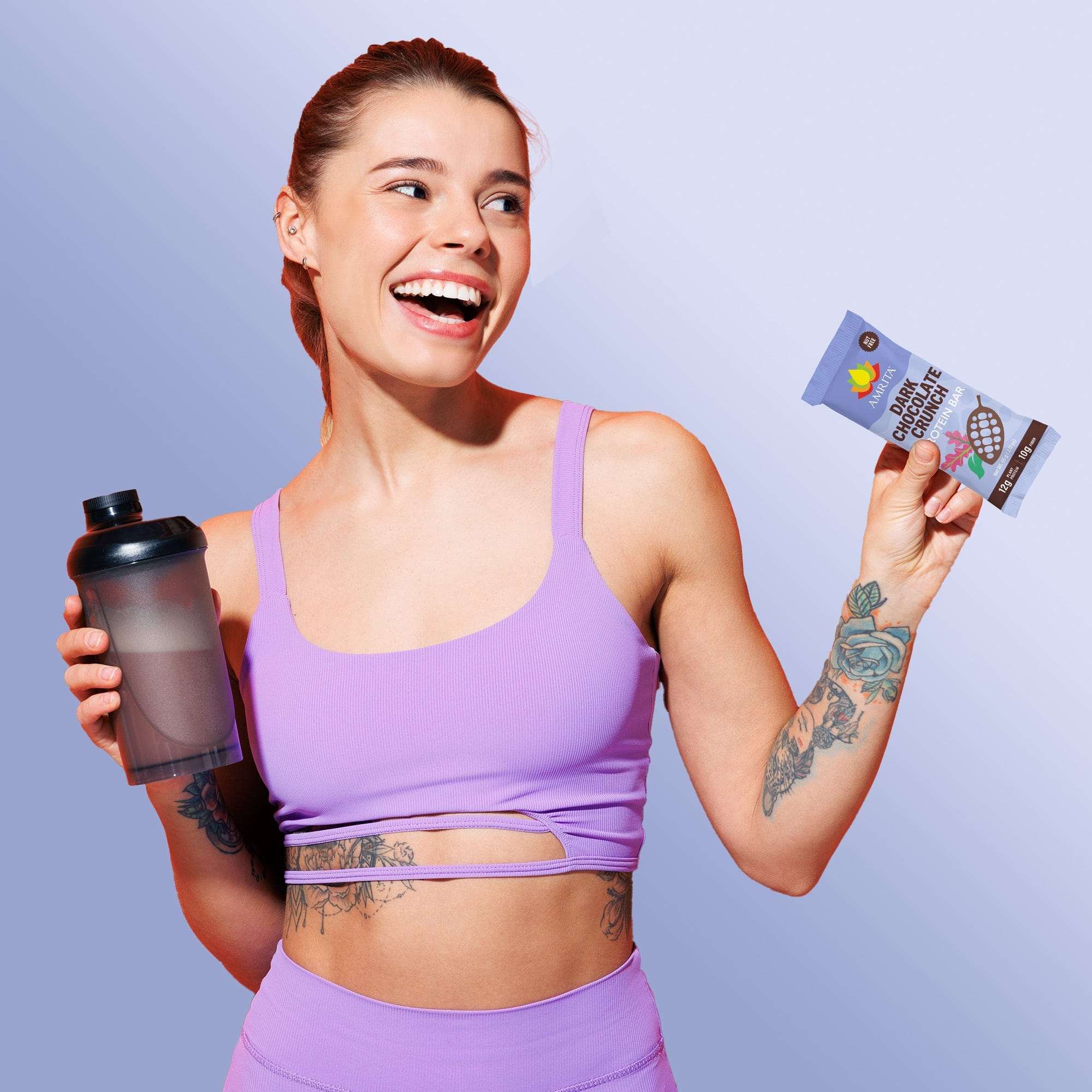 Dark Chocolate Crunch protein snack bar in a printed wrapper, held beside a black shaker bottle by a smiling woman