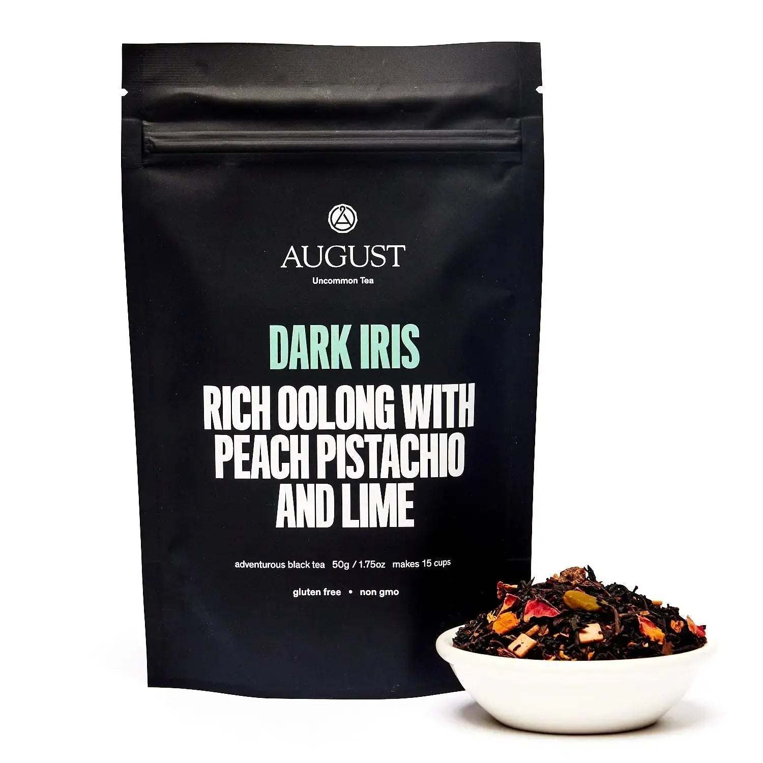Dark Iris - Peach Pistachio Oolong Tea in a black resealable pouch with a bowl of dark loose tea and colorful pieces