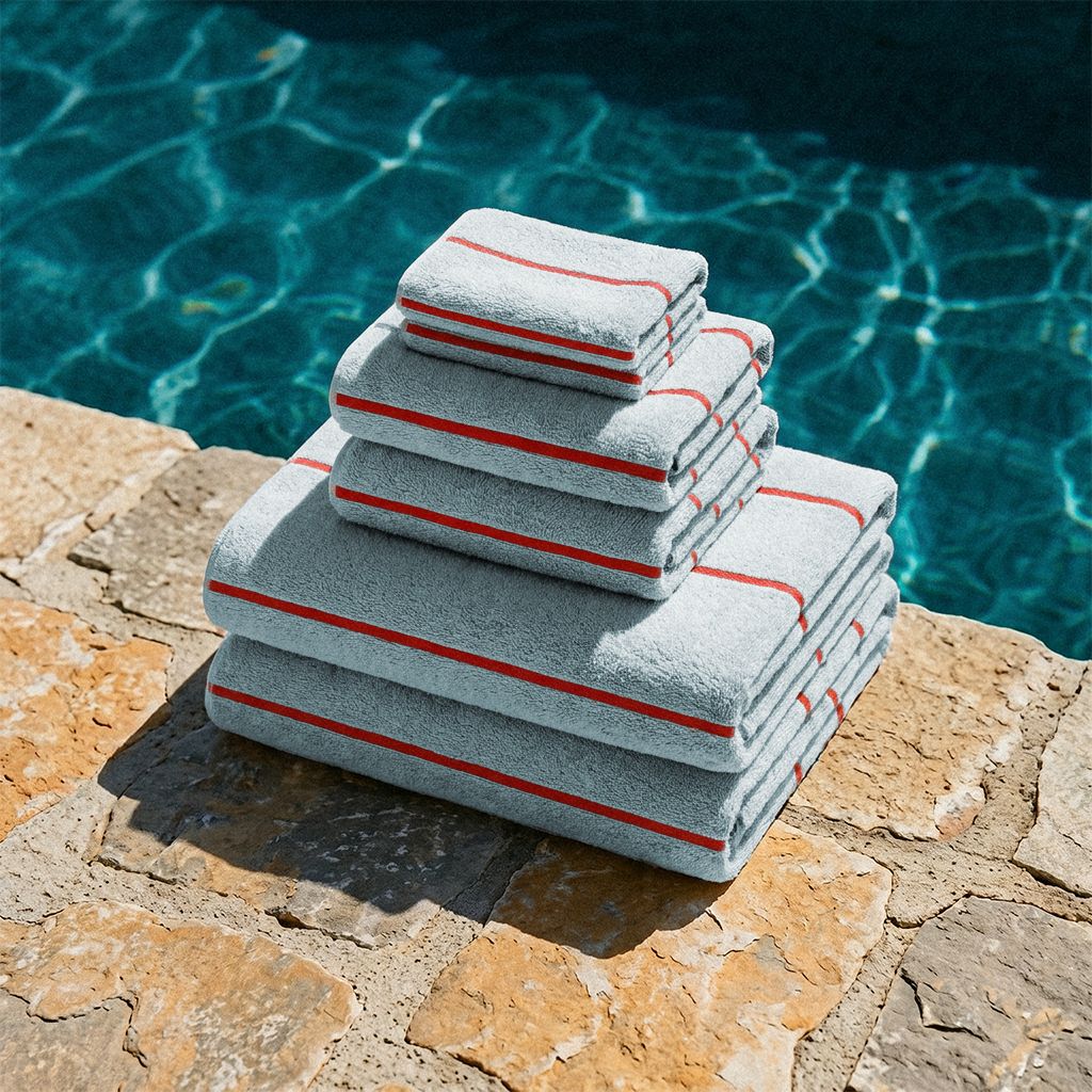Deia Australian Cotton towels in pale blue with red stripe trim, plush terry texture, and neatly folded edges