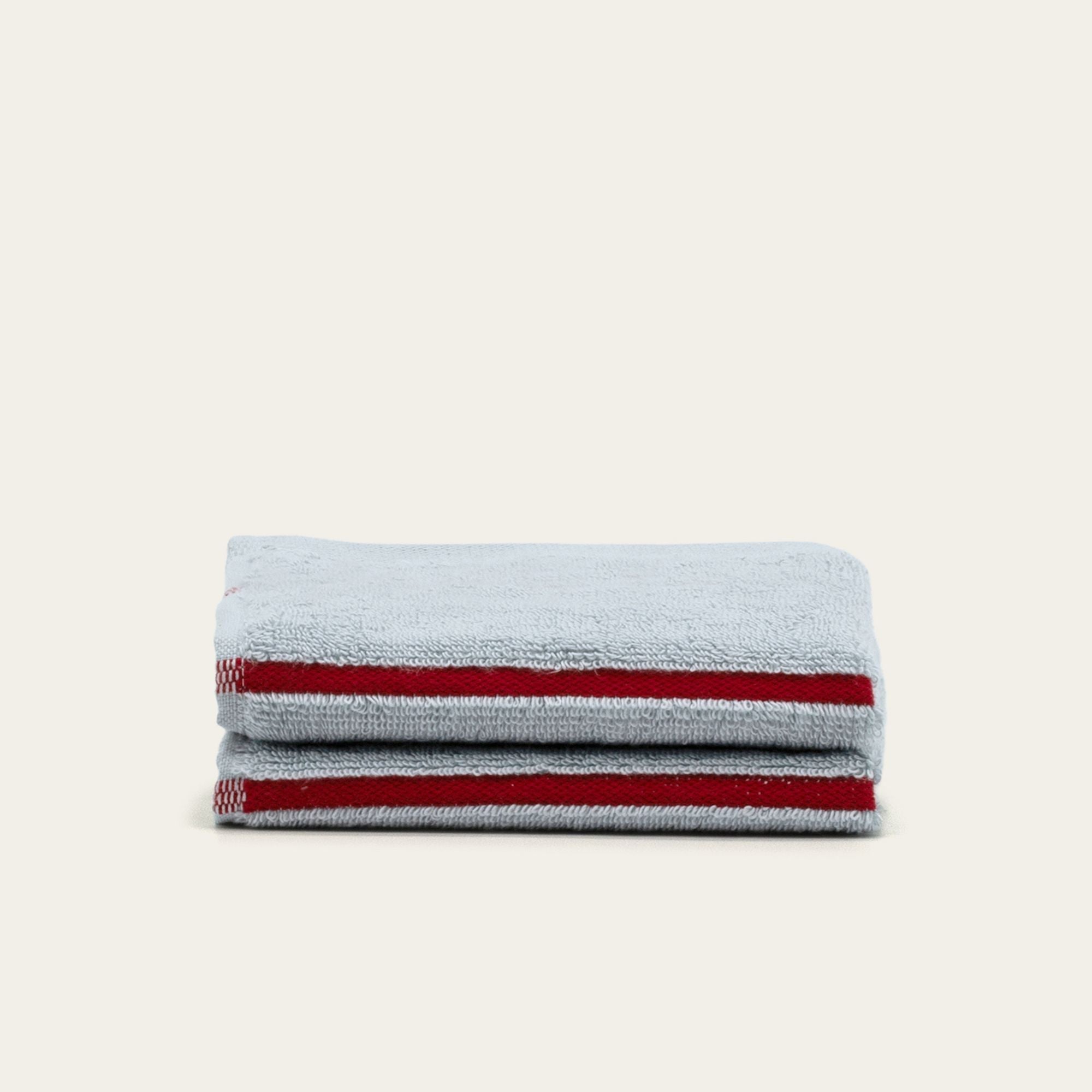 Deia Australian Cotton towel in pale blue terry cotton with bold red stripes along the hem, neatly folded