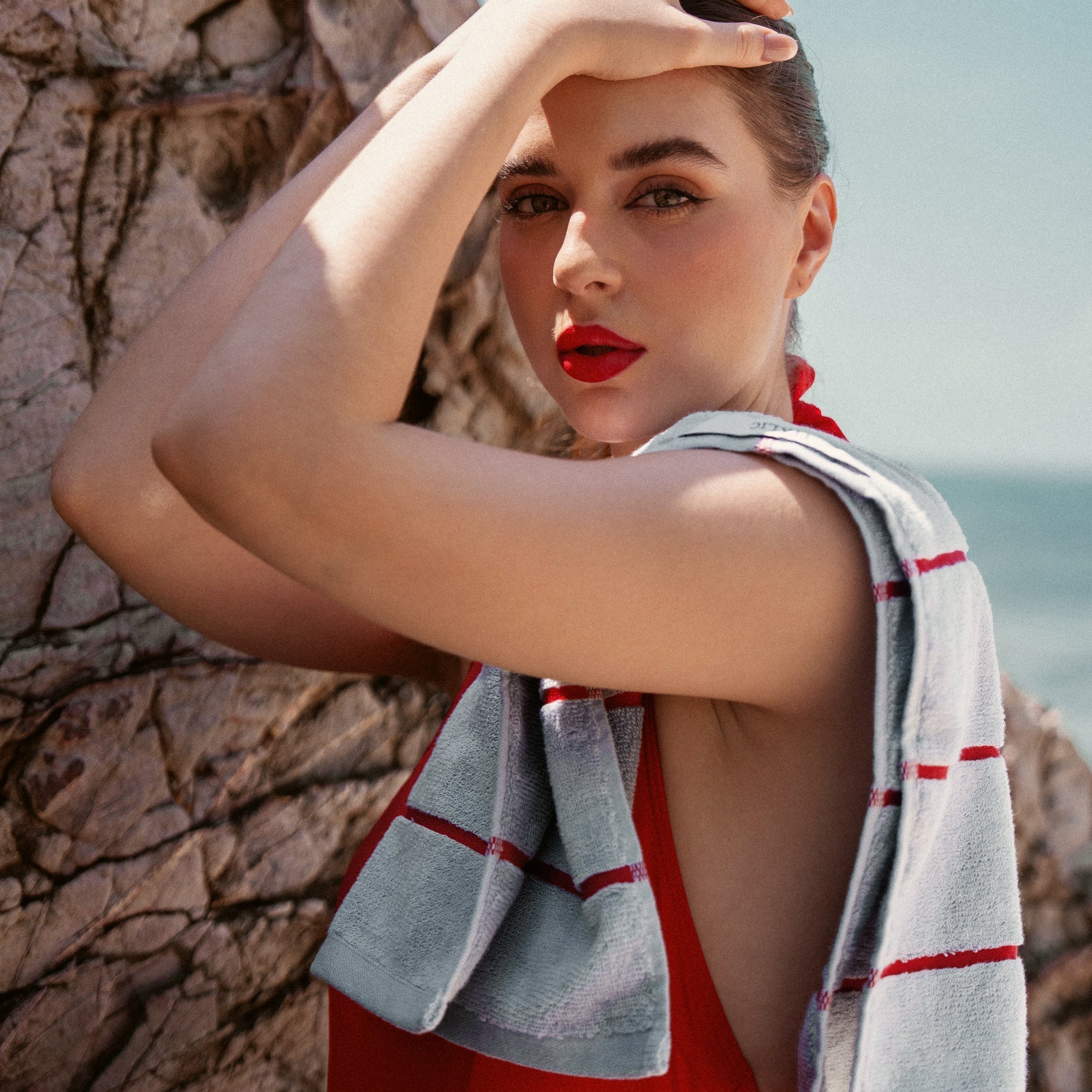 Deia Australian Cotton towel in pale blue-white terry with bold red horizontal stripes, draped over a shoulder