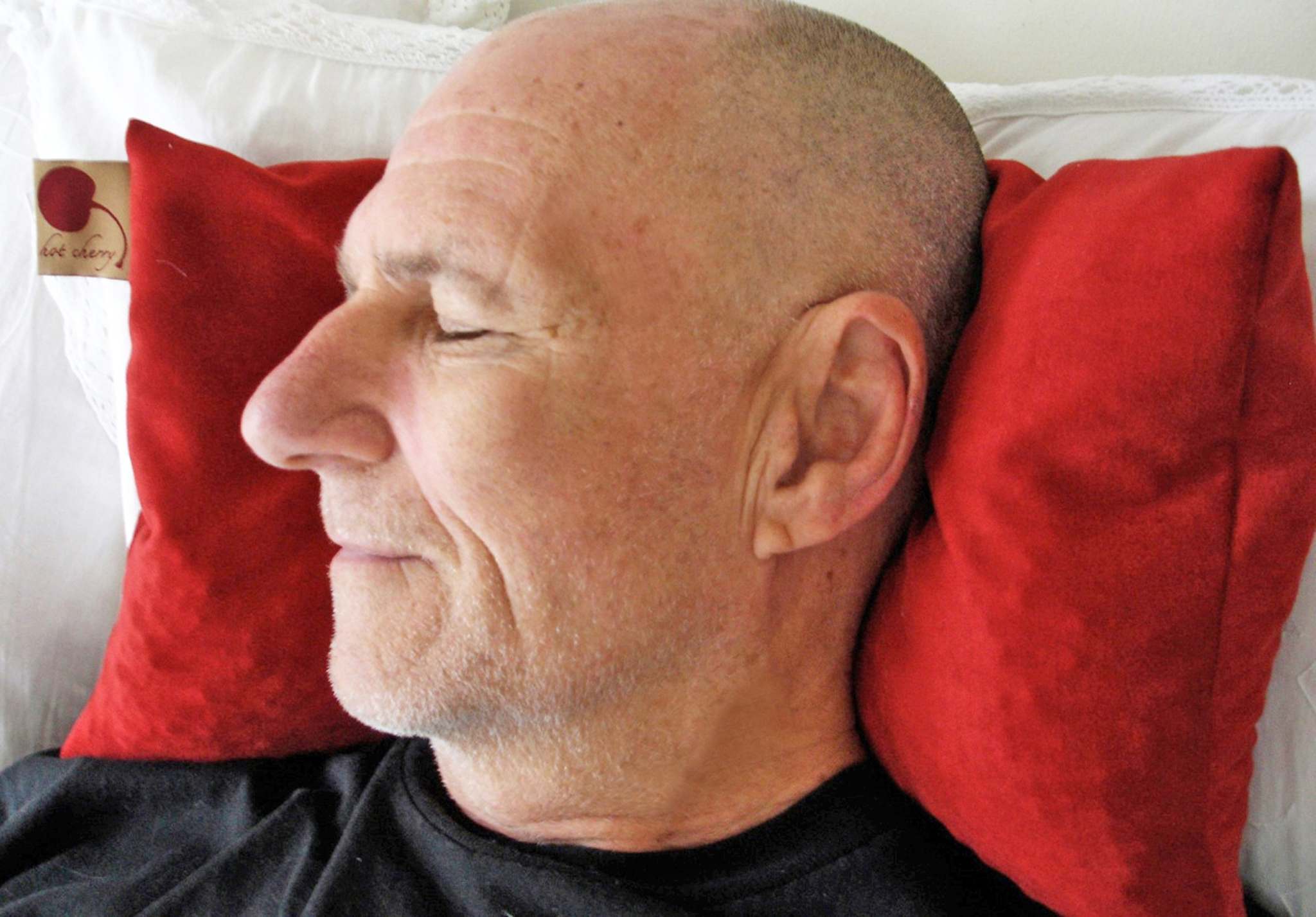 Double Square Pillow in rich red plush ultra-suede, shown cushioning a man's head and neck