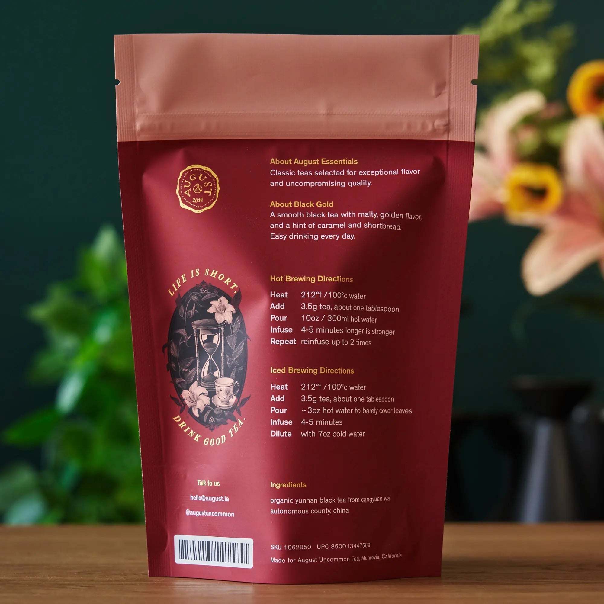 Essentials Black Gold Tea in a burgundy matte pouch with pink seal, gold text, and illustrated tea artwork