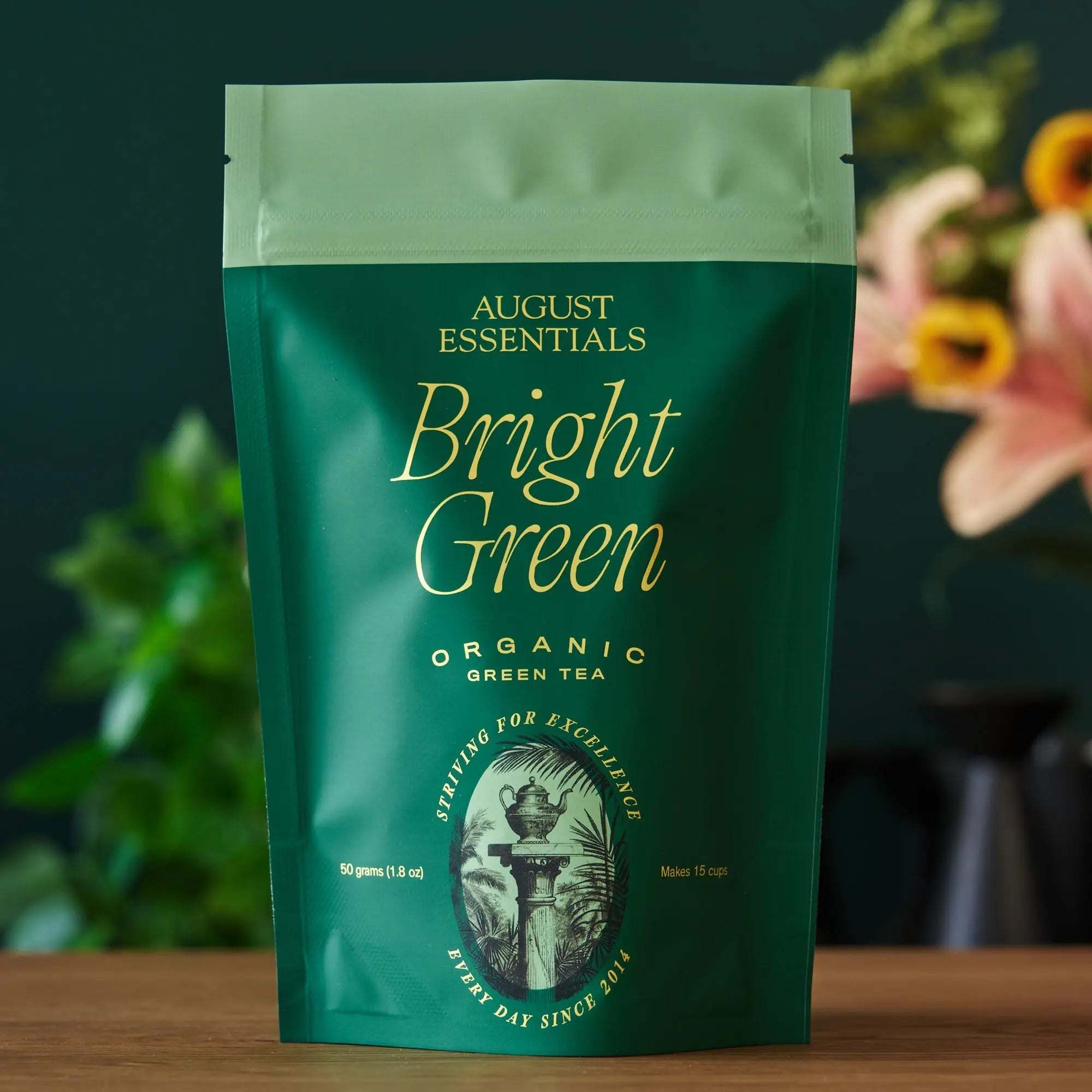Essentials Bright Green Tea in a dark green organic tea pouch with gold lettering and vintage emblem detailing