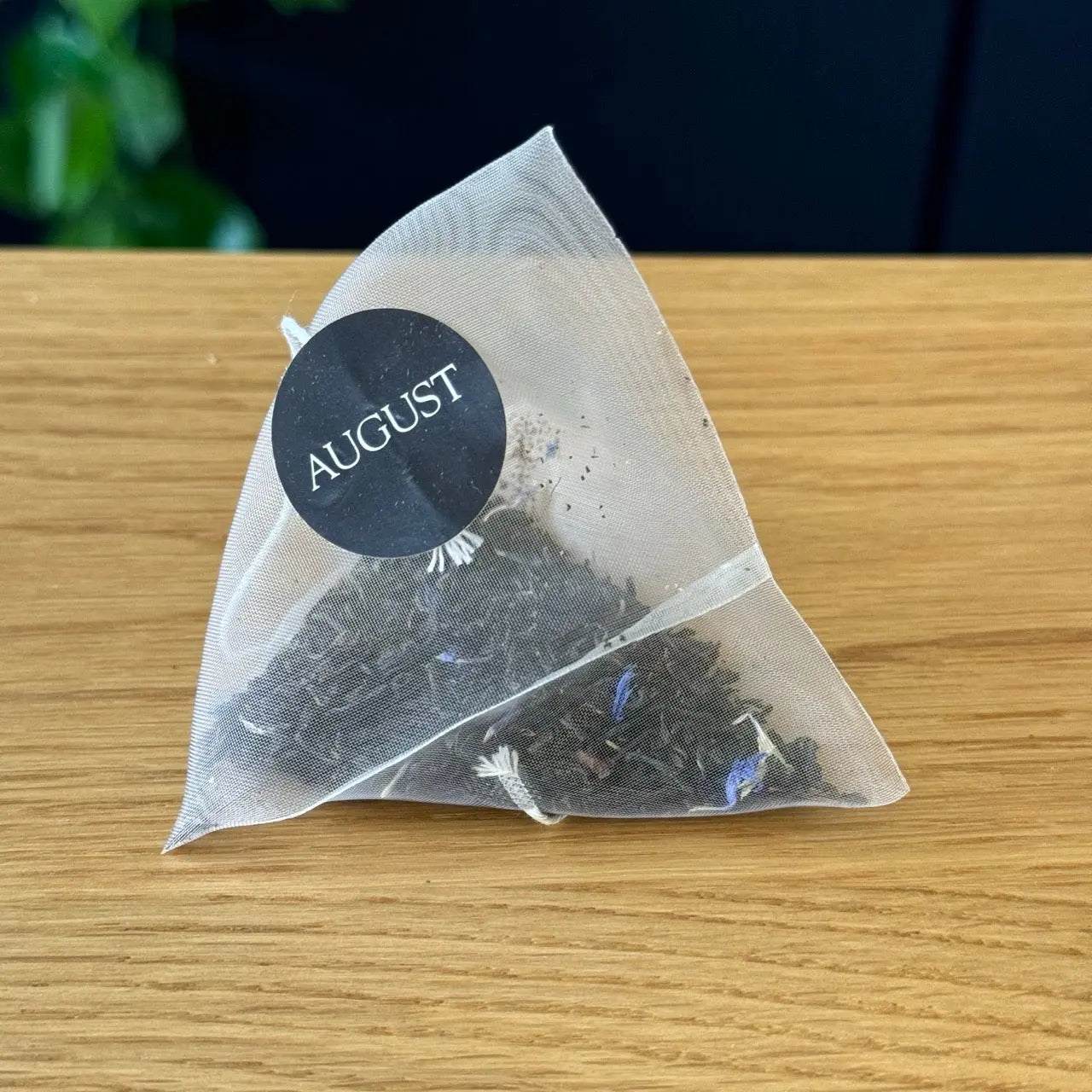 Essentials Earl Grey Black Tea pyramid sachet with loose black tea leaves and blue cornflower petals