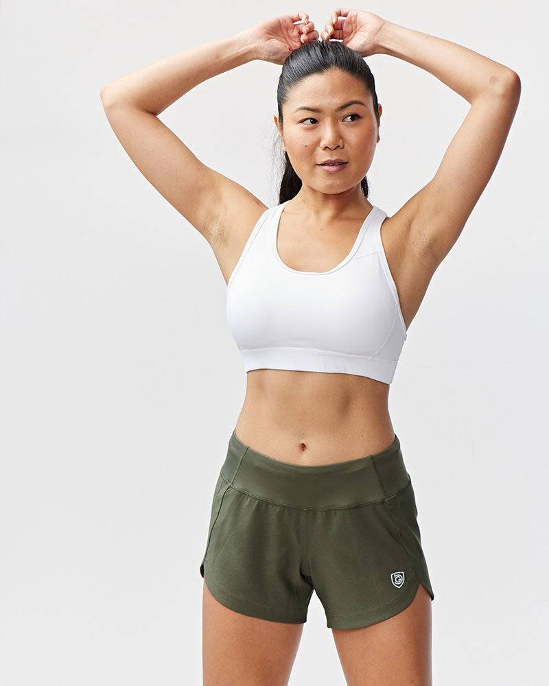 Excel Women's Workout Shorts in olive green stretch fabric, featuring a wide waistband and relaxed fit with curved hems.