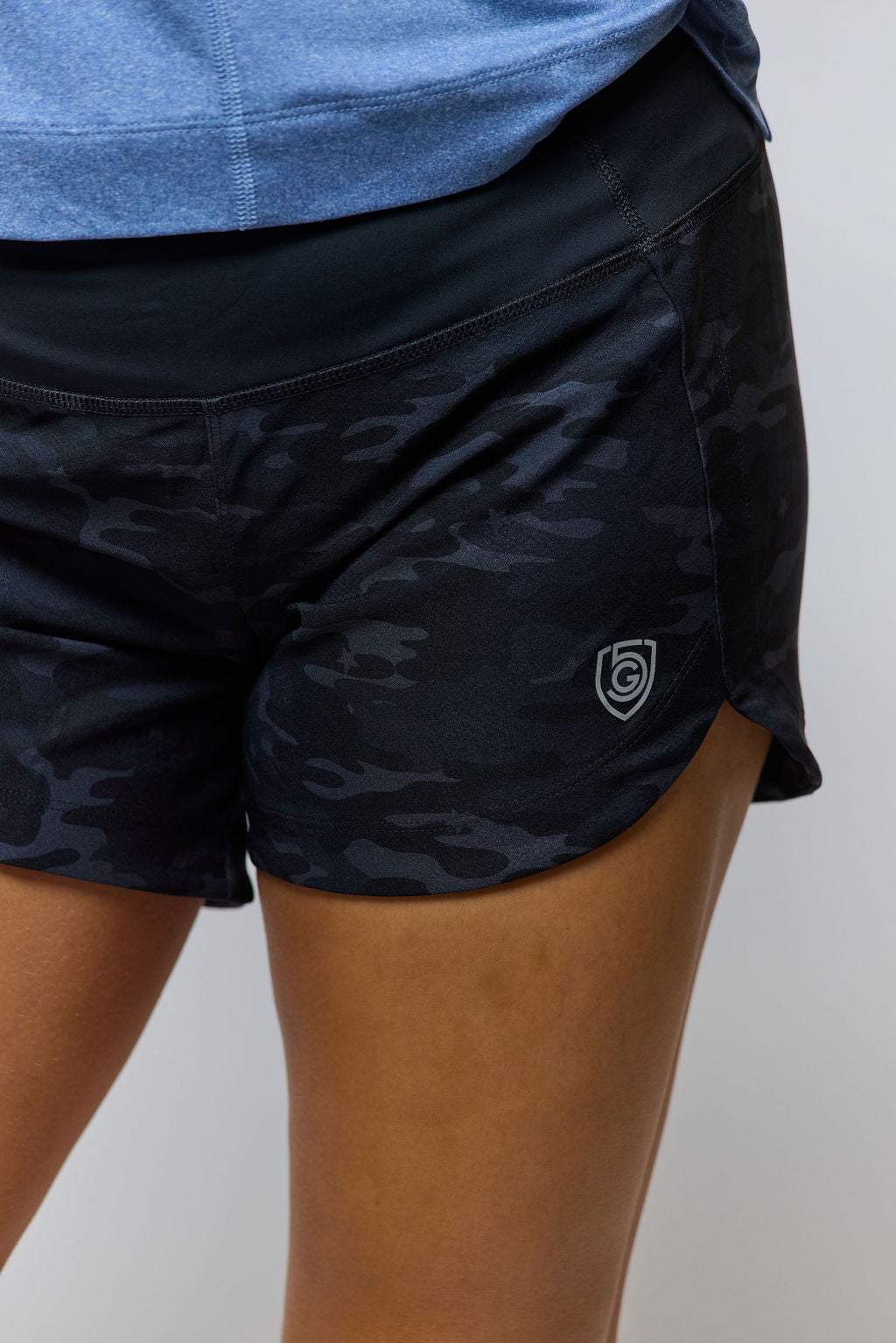 Excel Women's Workout Shorts in black with a subtle tonal camouflage pattern, stretchy fabric, wide waistband and side logo