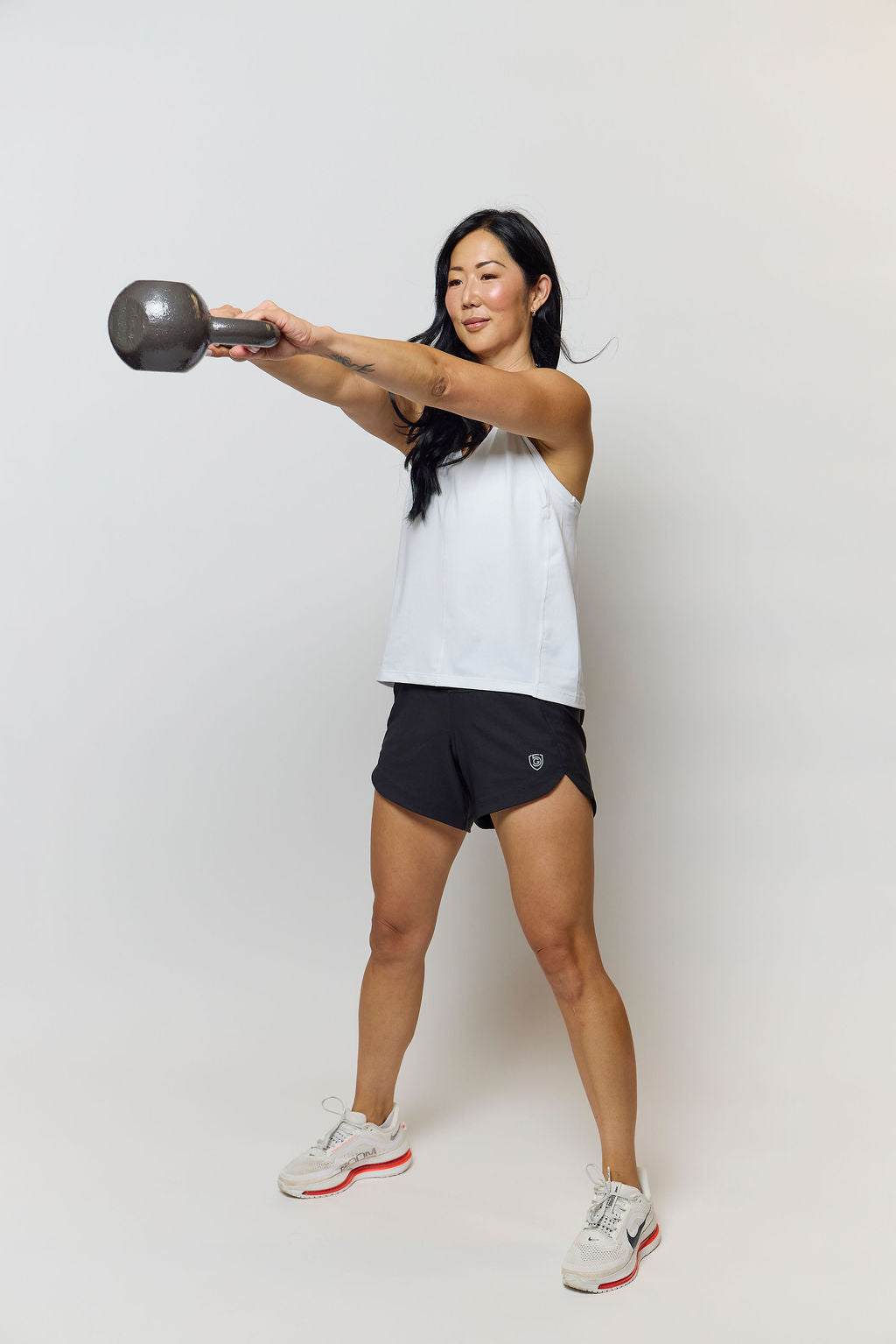 Excel Women's Workout Shorts in black stretch fabric with a relaxed fit and curved side hems, worn during kettlebell training