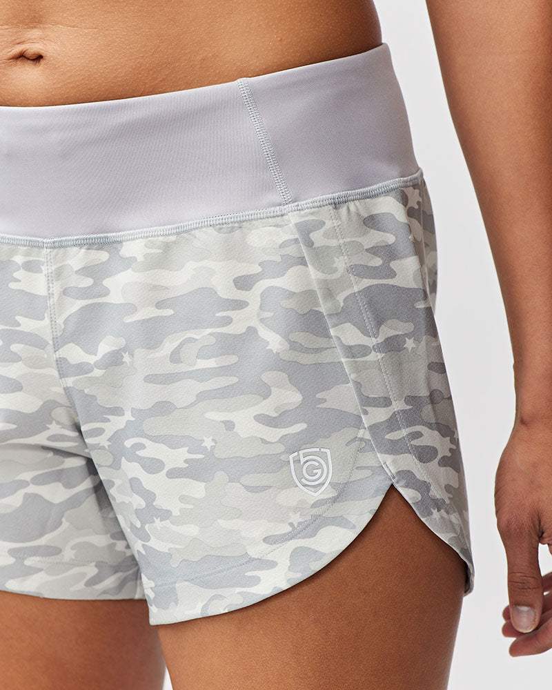 Excel Women's Workout Shorts in light gray camouflage fabric with a wide pale waistband, curved hems, and small logo