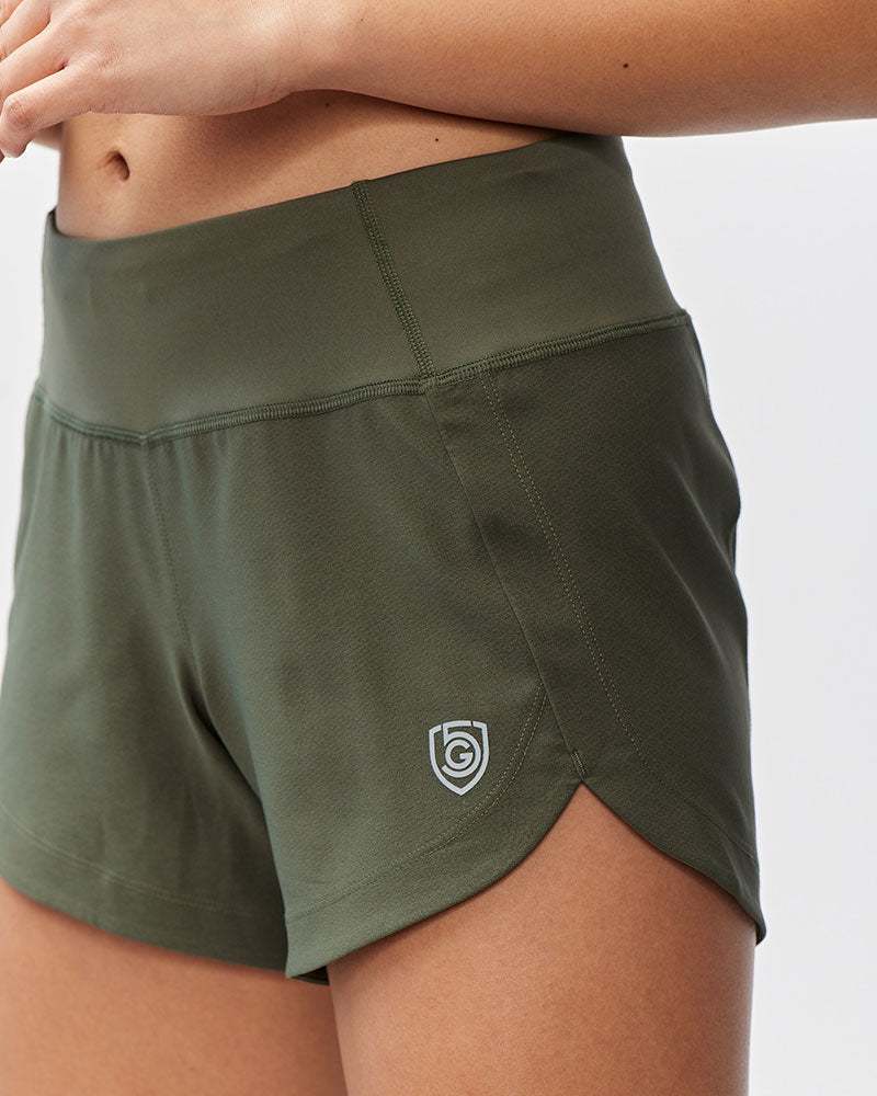 Excel Women's Workout Shorts in olive green stretch fabric, featuring a wide high-rise waistband and curved split hems