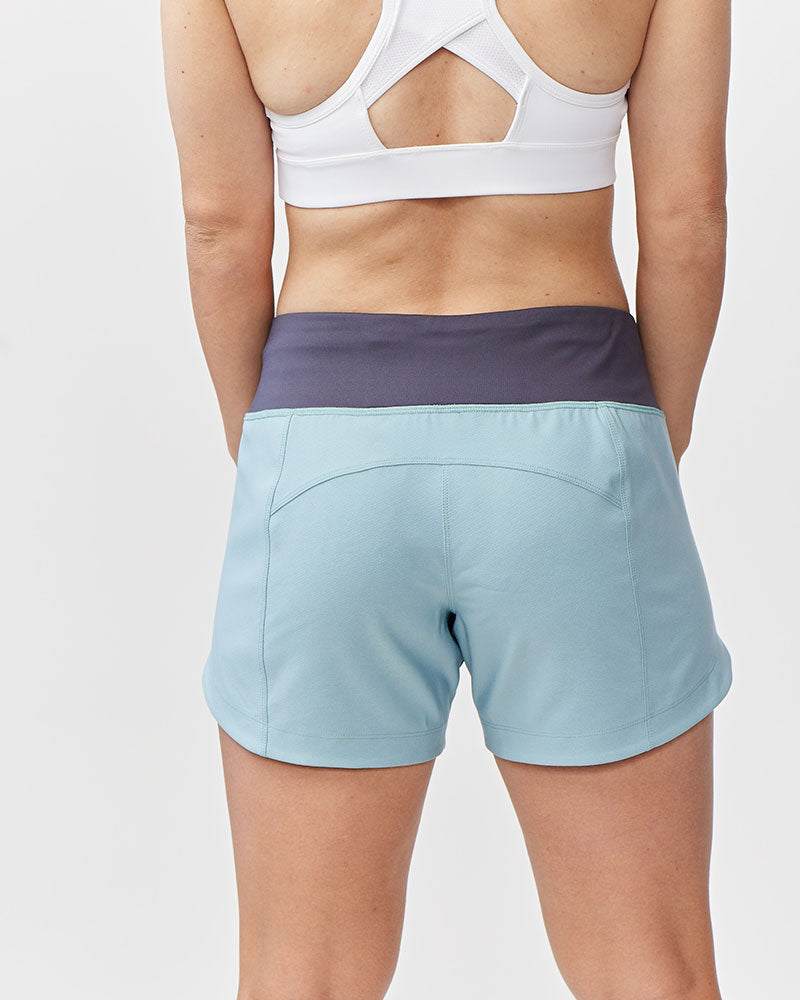 Excel Women's Workout Shorts in pale blue stretch fabric with a wide charcoal waistband and curved hem