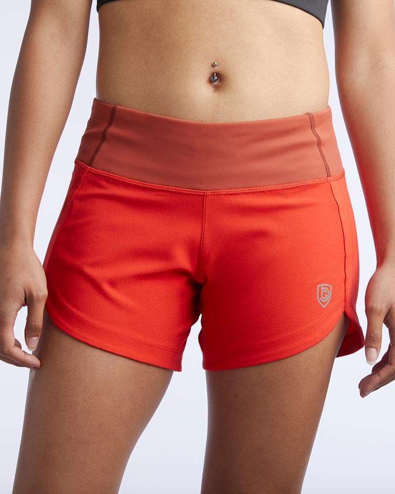 Excel Women's Workout Shorts in bright red stretch fabric with a wide contrasting waistband, side slits and small logo