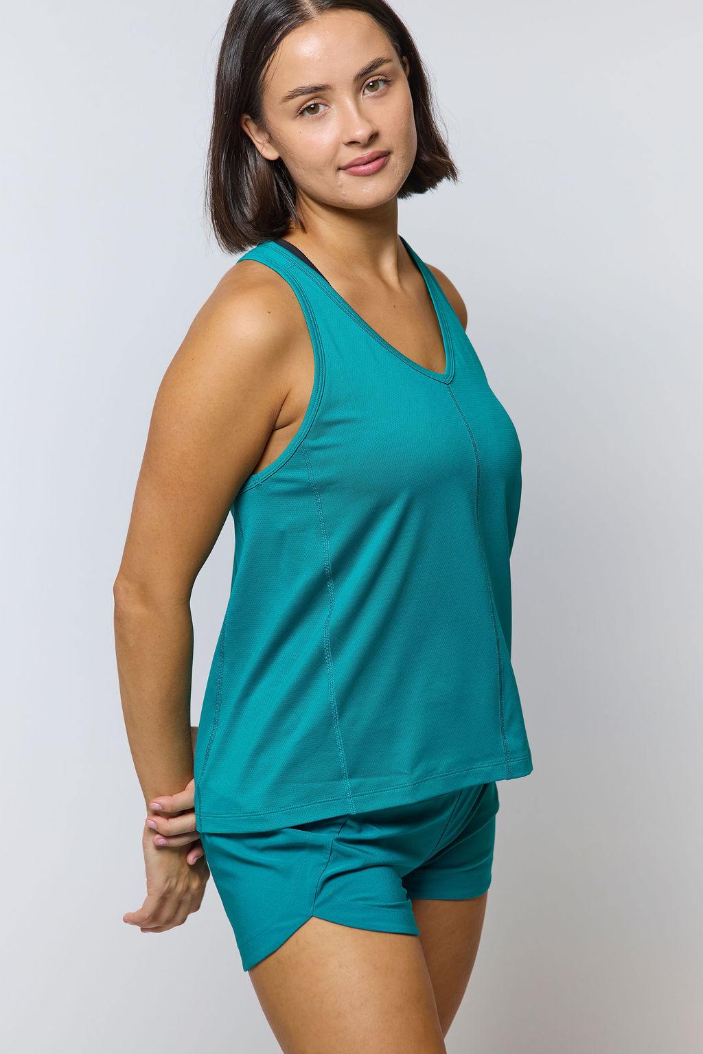 Excel Women's Workout Shorts in teal stretch fabric, shown with a matching sleeveless tank and crossover front hem