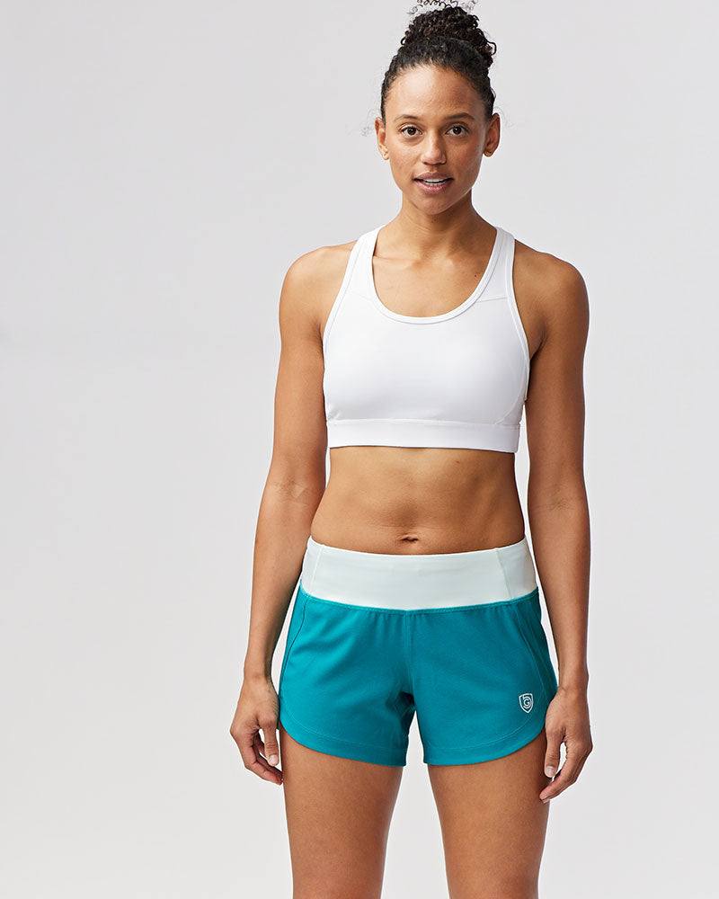 Excel Women's Workout Shorts in teal stretch fabric, featuring a wide white waistband and relaxed athletic fit