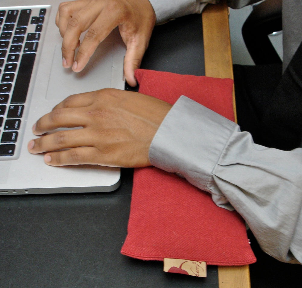 Eye Pillow in Red Denim fabric placed on desk supporting wrist near laptop, soft textured and rectangular shape