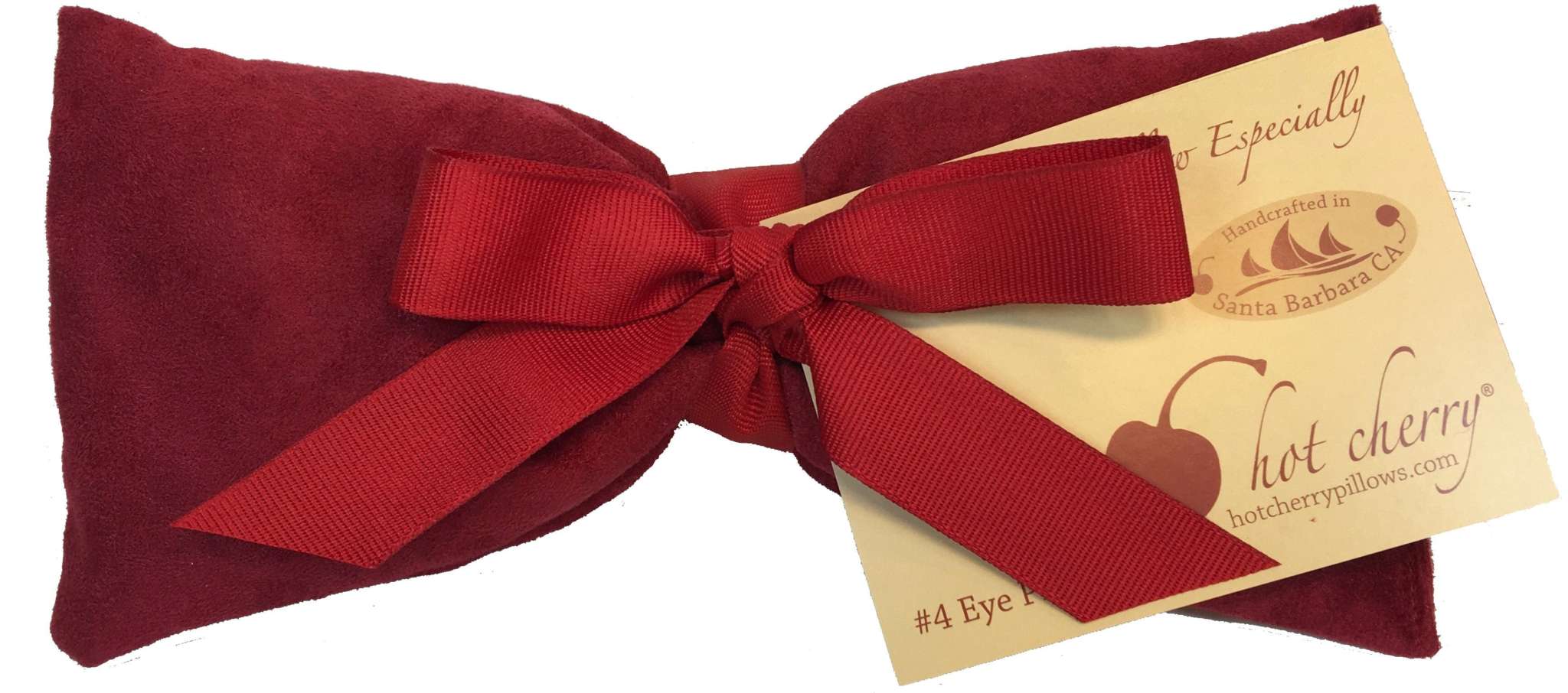 Eye Pillow in plush deep red ultra-suede fabric with a matching red ribbon tied around it and a beige gift tag attached.