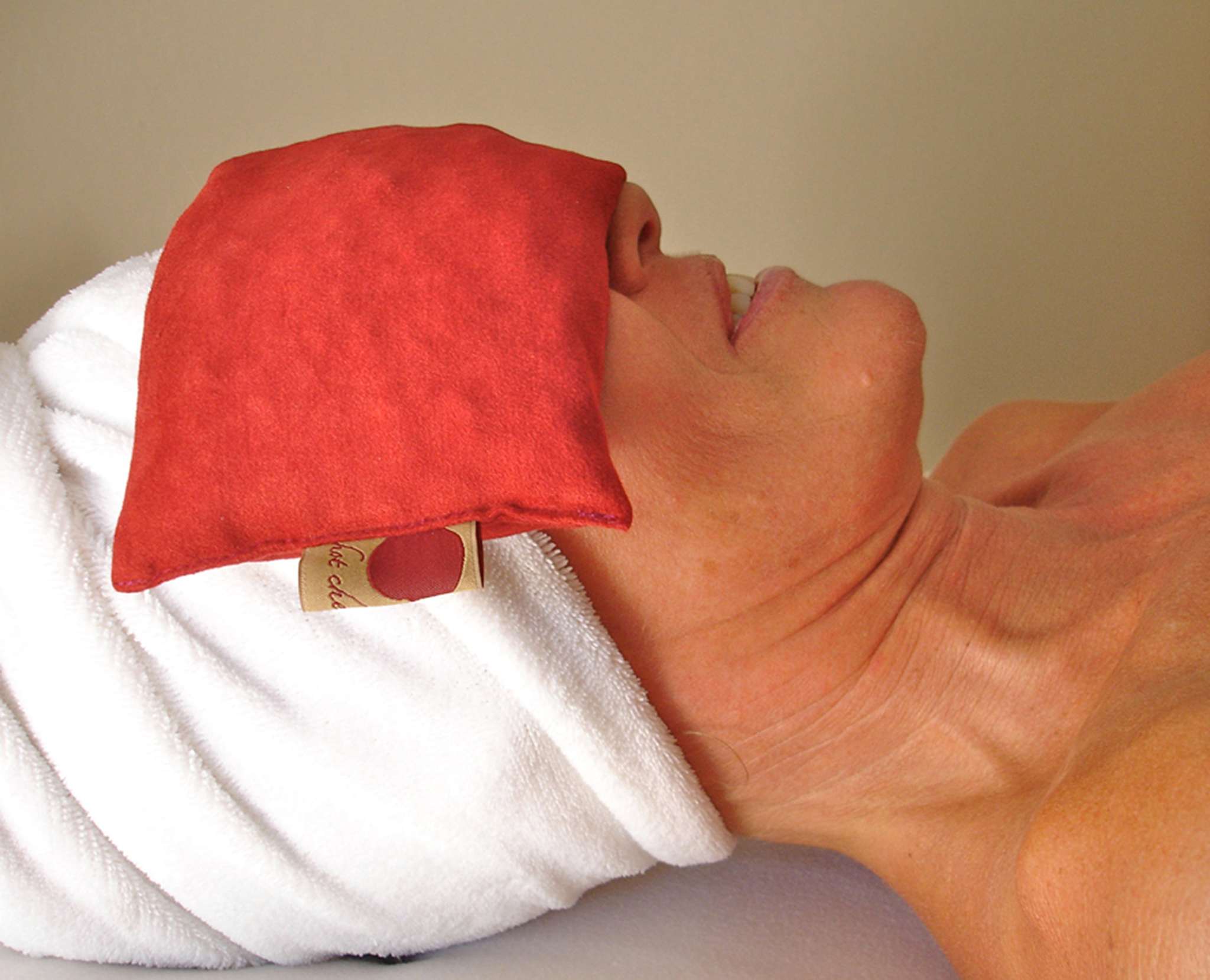 Eye Pillow in plush red ultra-suede fabric designed for relaxation and headache relief, rectangular shape.