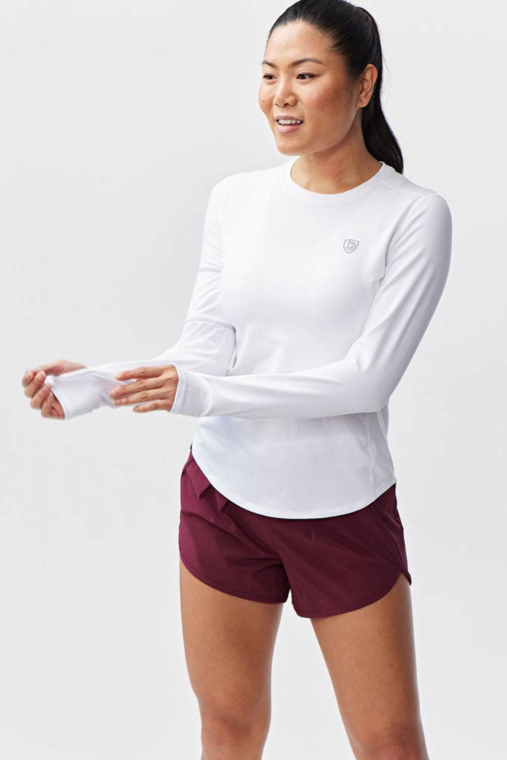 Foudy Women's Longsleeve workout top in white, with a smooth fitted design, long sleeves, thumbholes and curved hem