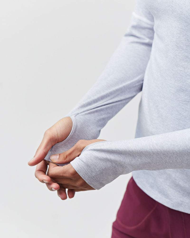 Foudy Women's Longsleeve workout top in light heather gray, with long sleeves and extended cuffs covering the hands