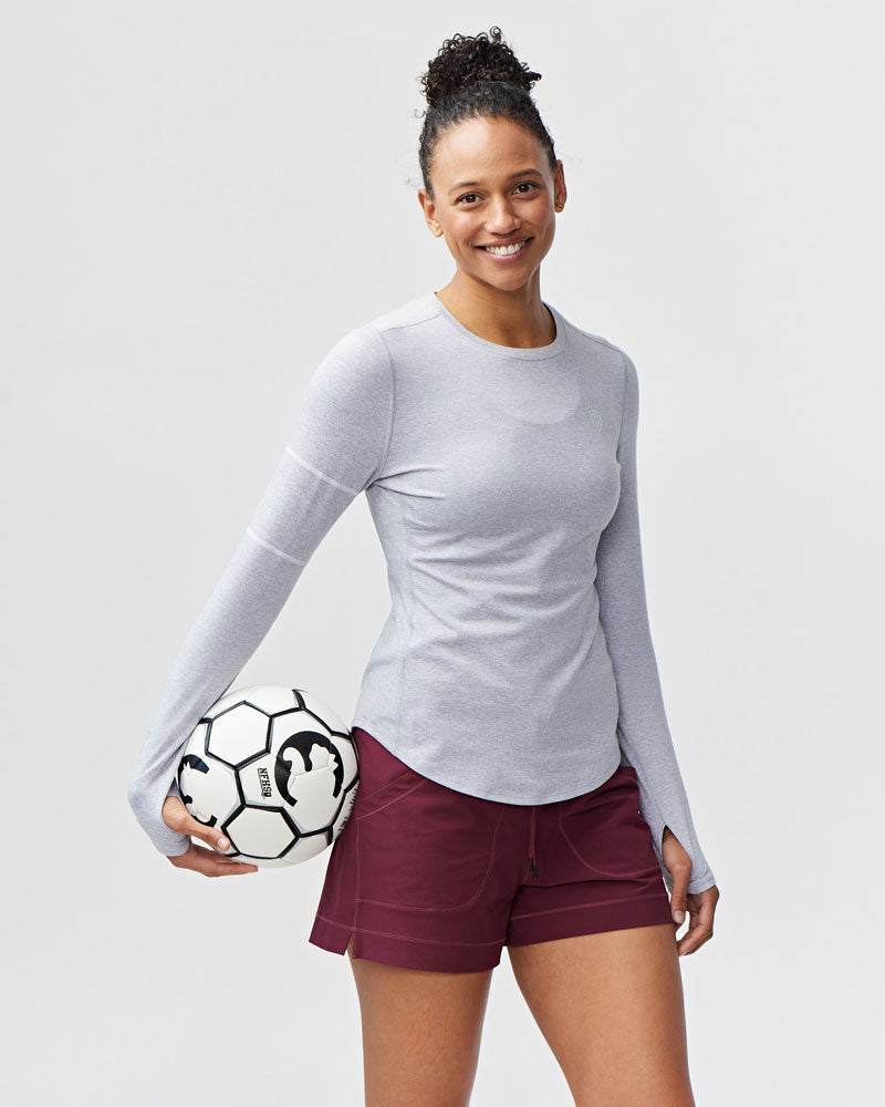 Foudy Women's Longsleeve workout top in light gray, fitted with long sleeves and a curved hem, paired with burgundy shorts