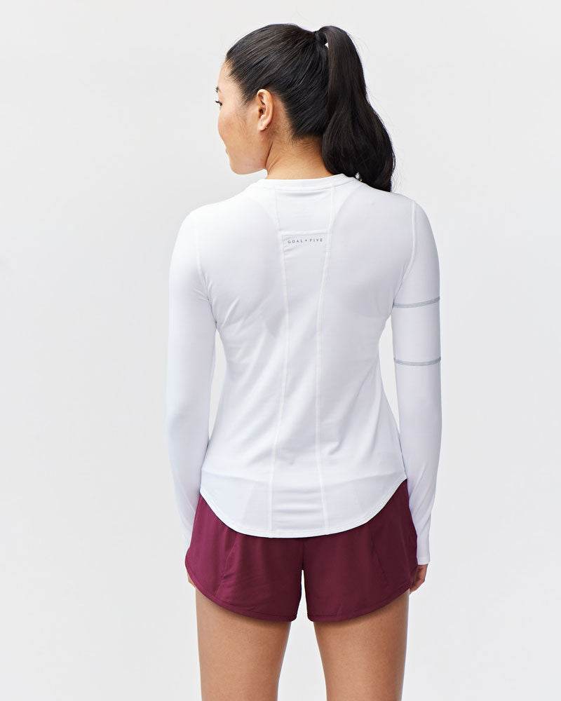 Foudy Women's Longsleeve workout top in white with long sleeves, curved hem, and captain’s seam detailing on the upper arm