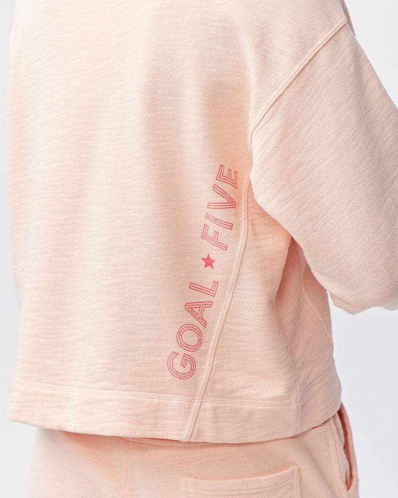 Freasy Crew sweatshirt in pale peach, with soft-looking fabric, a relaxed fit and vertical Goal Five lettering