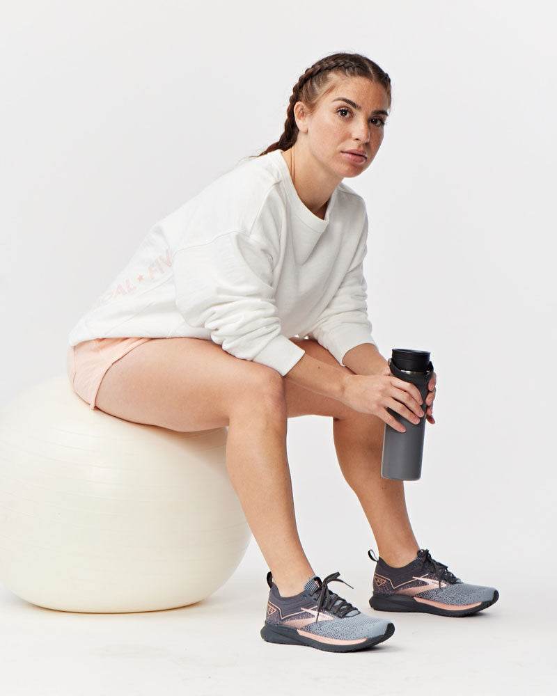Freasy Crew sweatshirt in white with a relaxed fit and ribbed cuffs, paired with pink shorts and running shoes