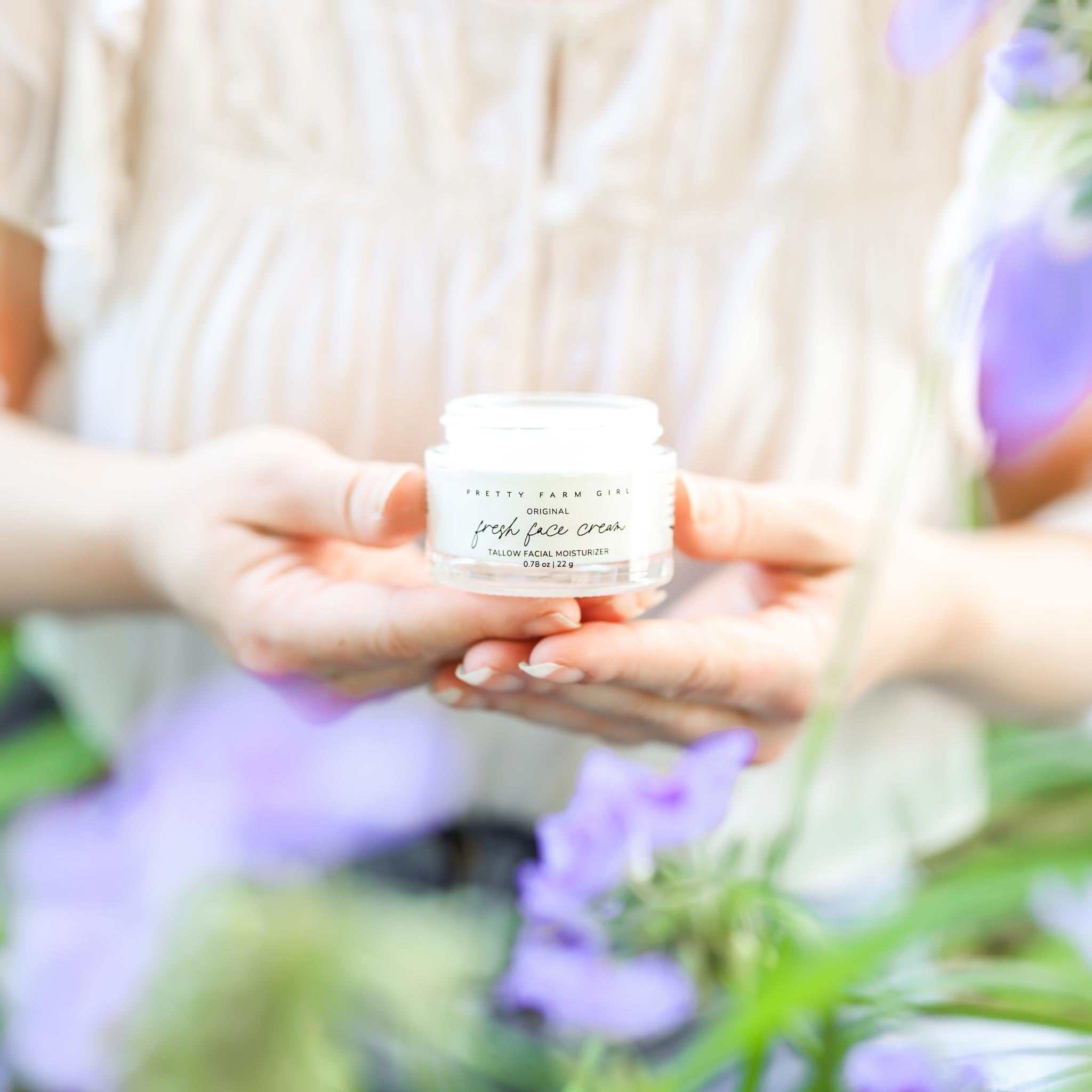 Fresh Face Cream in a small white glass jar with a white lid and a simple black label, held in two hands