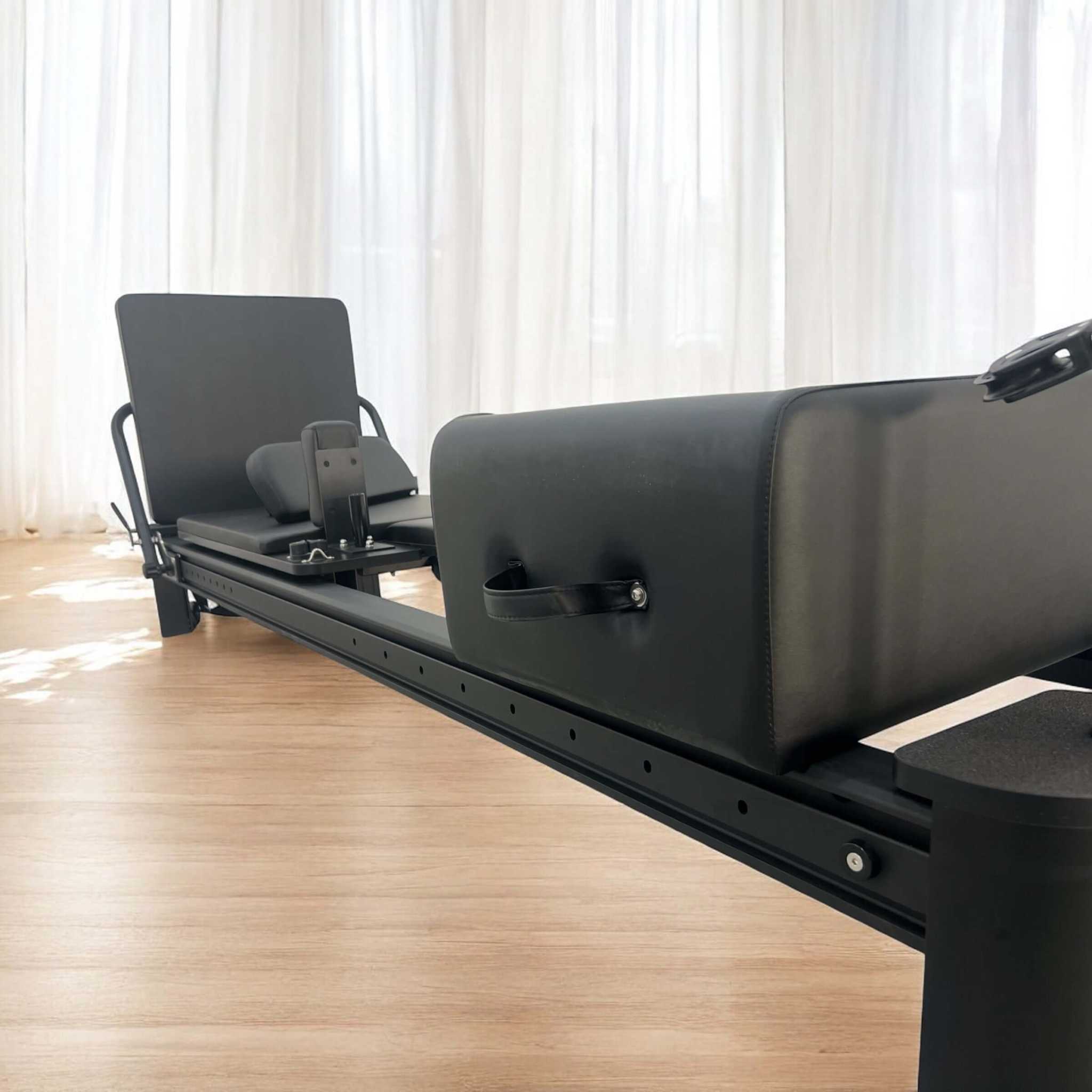 Full Track Queen Studio Pilates Reformer with black frame and upholstery