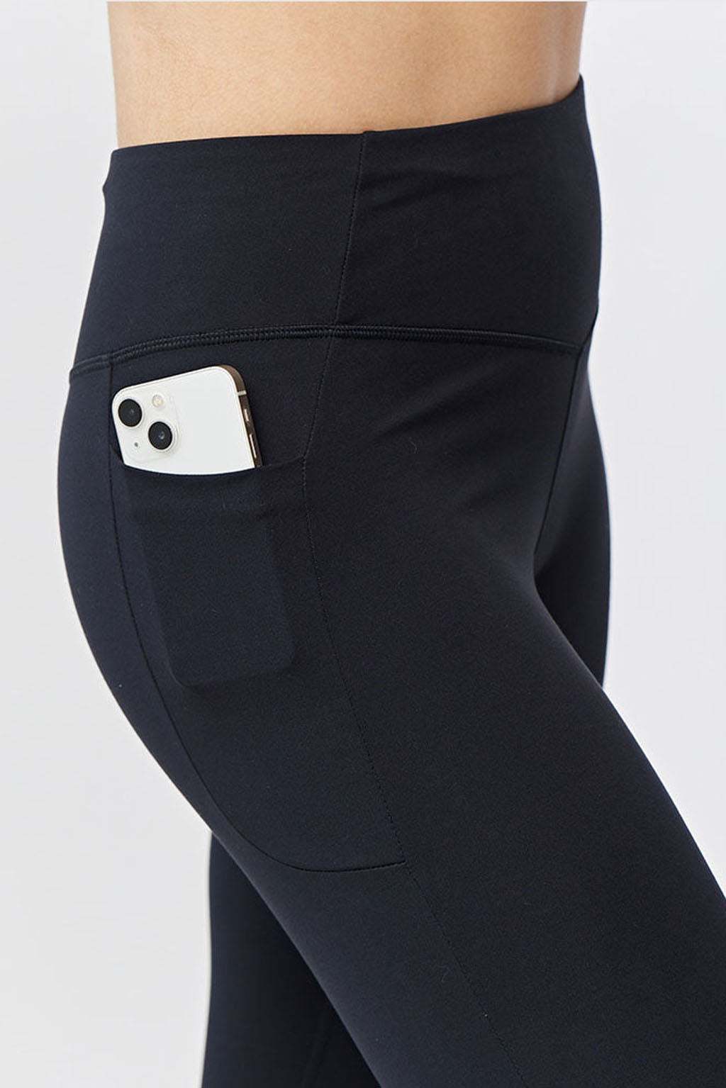 Go Again Crop Legging in black stretch fabric with a high-rise waistband, smooth finish, and side pocket holding a phone