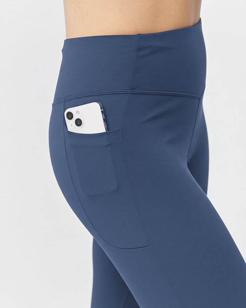 Go Again Crop Legging in solid navy stretch fabric with a high-rise waistband and a side pocket holding a phone