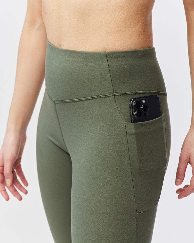 Go Again Crop Legging in olive green stretch fabric with a high-rise waistband and side pocket holding a phone