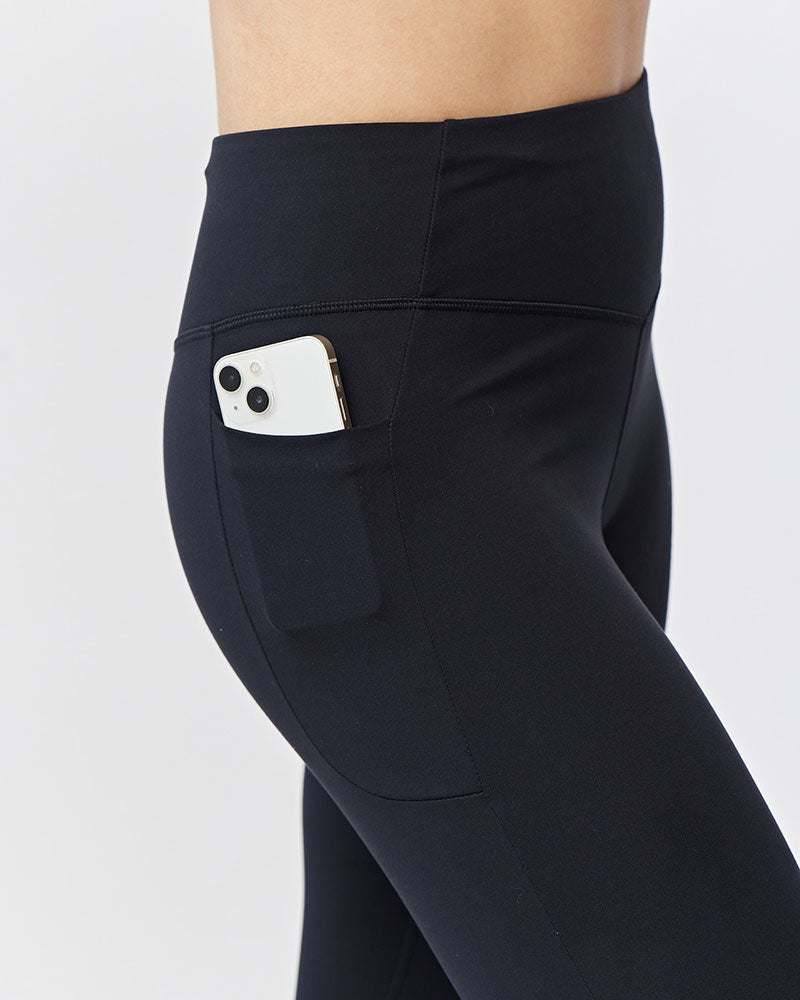 Go Again Full Length Legging in black stretch fabric with a high-rise waistband and side pocket holding a phone