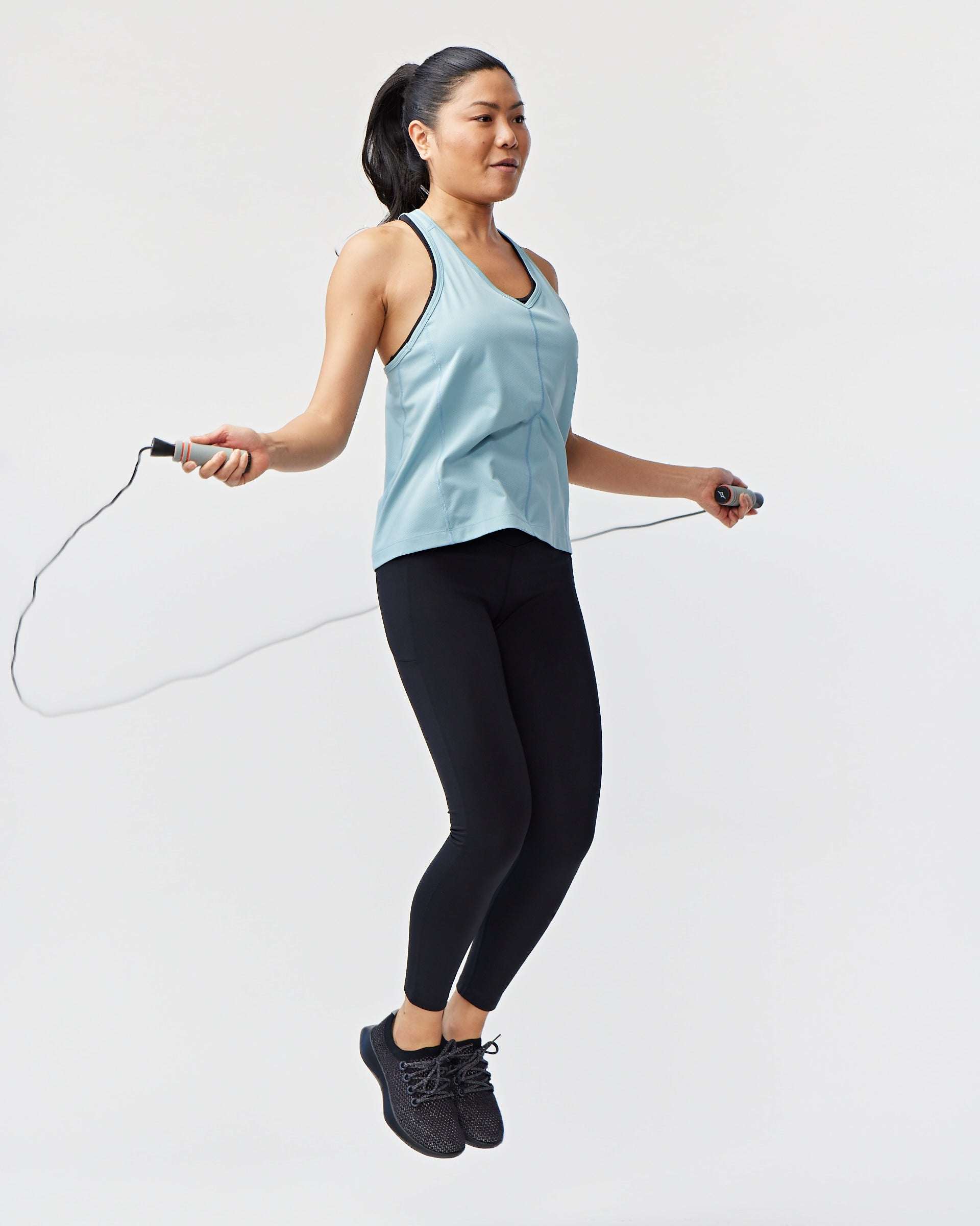 Go Again Full Length Legging in black stretch fabric, worn with a pale blue tank top while jumping rope