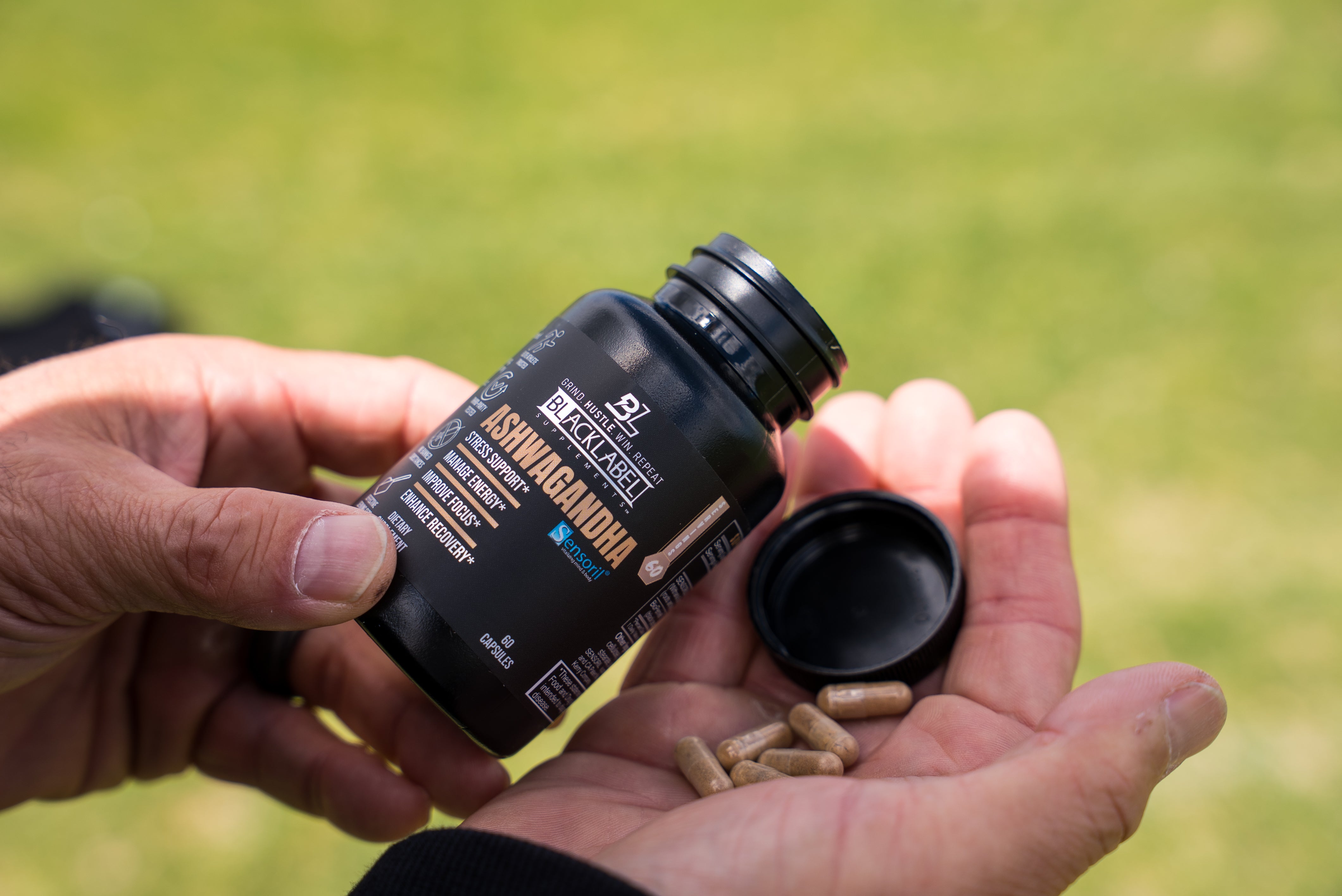 HEALTH & WELLNESS STACK featuring a black ashwagandha supplement bottle and loose brown capsules in an open palm