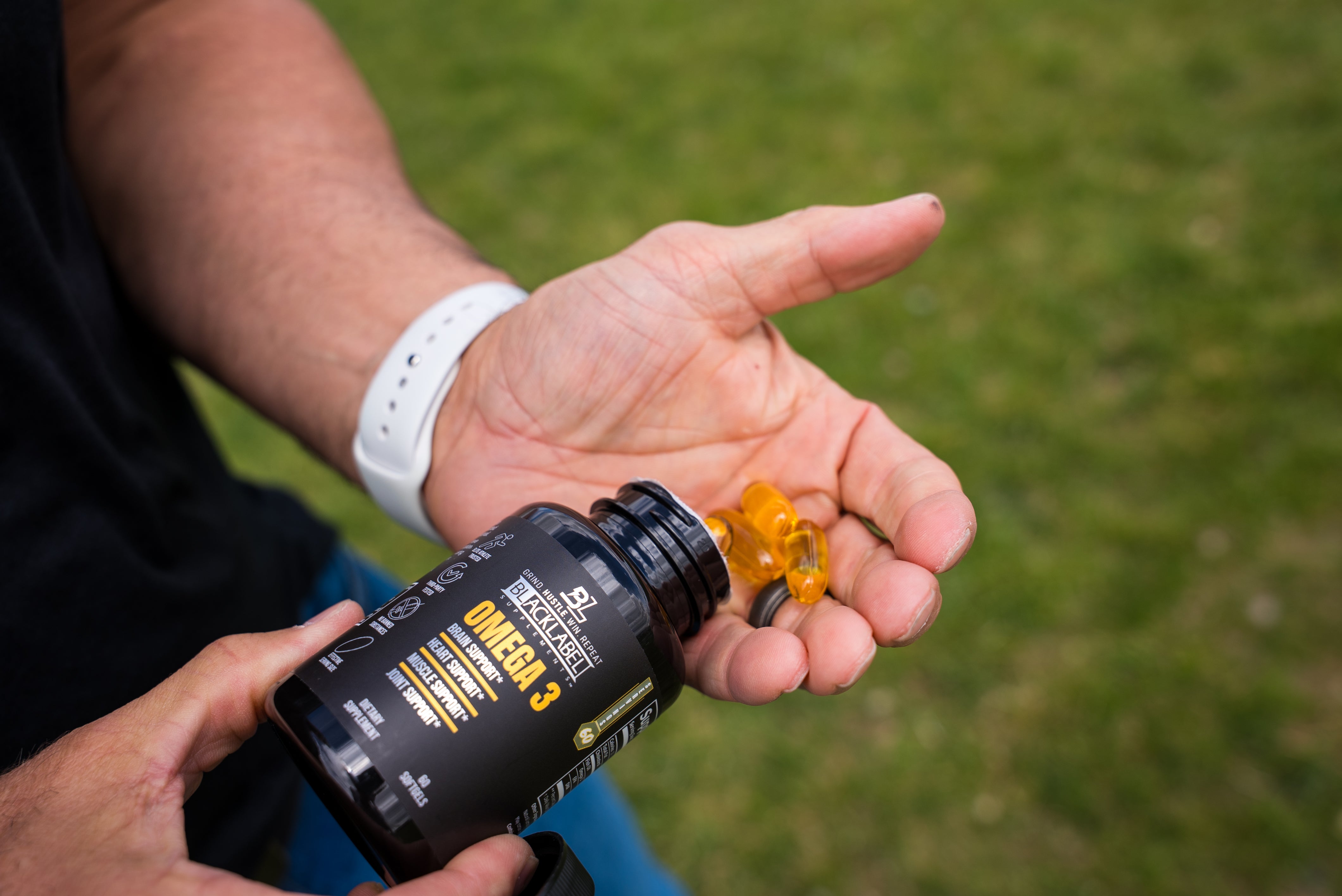 HEALTH & WELLNESS STACK Omega-3 supplement bottle with amber softgel capsules in a person's open hand