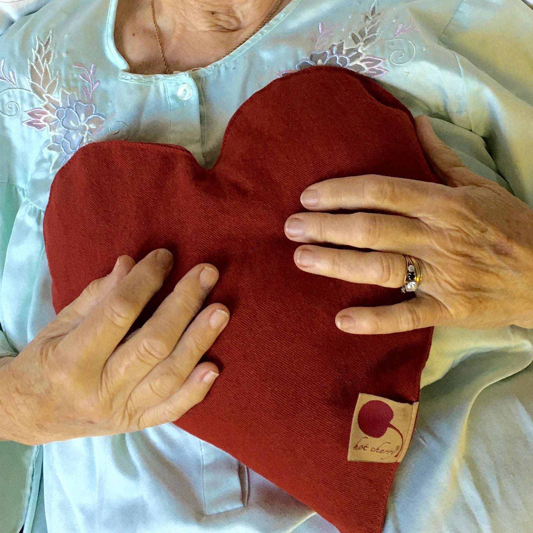 Heart-Shaped Pillow in deep red cotton denim with a soft, curved shape and branded fabric tag