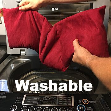 Heart-Shaped Pillow in deep red plush fabric, shown being held above a washing machine to highlight its washable design