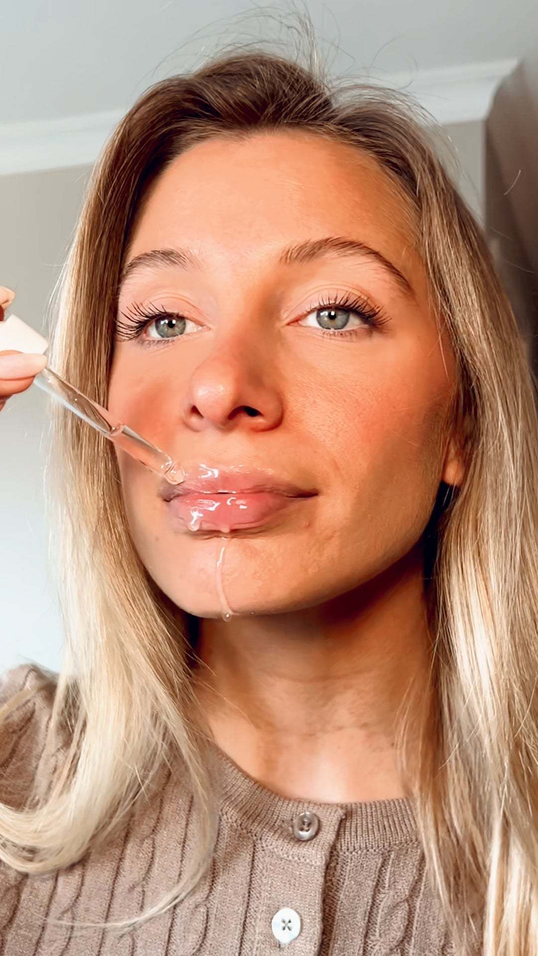 Hyaluronic Acid Plumping Serum, clear hydrating serum visibly applied to lips with a glass dropper applicator