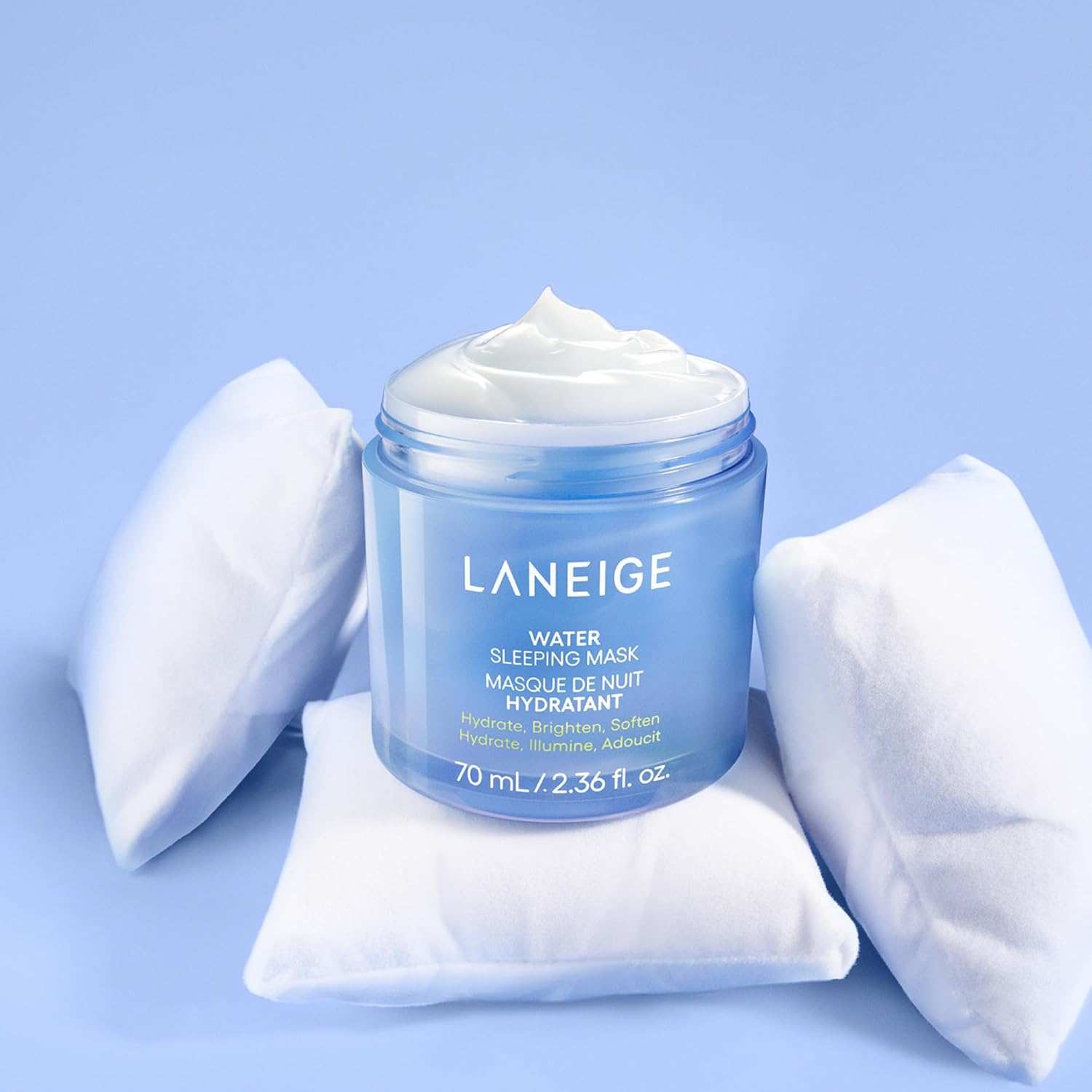 Laneige Water Sleeping Mask in a translucent blue jar with white creamy texture on top surrounded by three small white pillows