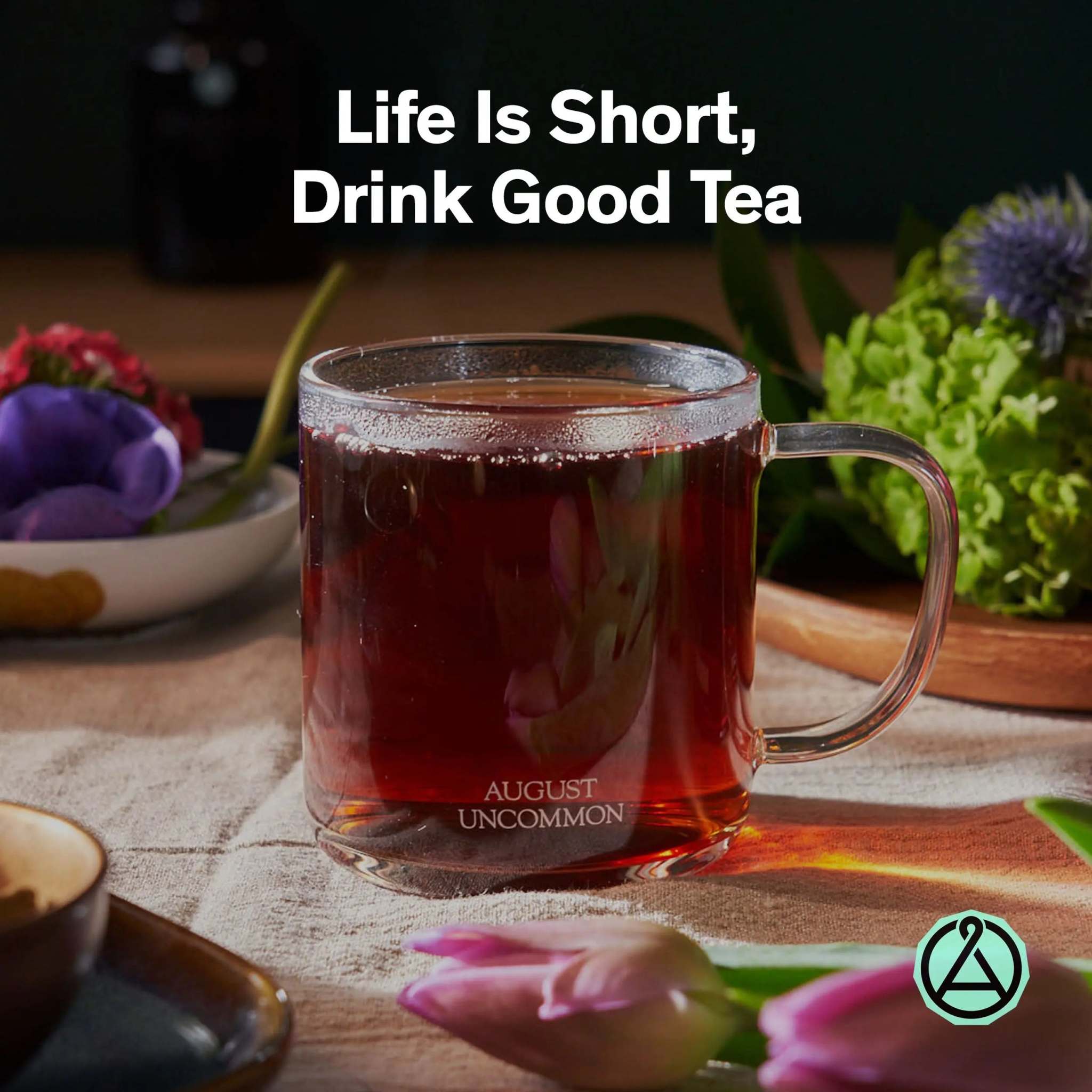 Low Country Black Tea in a clear glass mug, showing a deep amber-brown brew and visible August Uncommon branding.