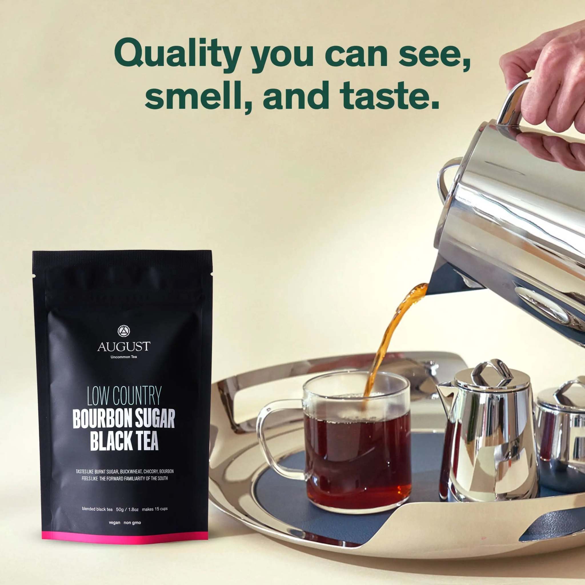 Low Country Black Tea in a black resealable pouch, with brewed tea poured into a glass cup beside a silver tea set