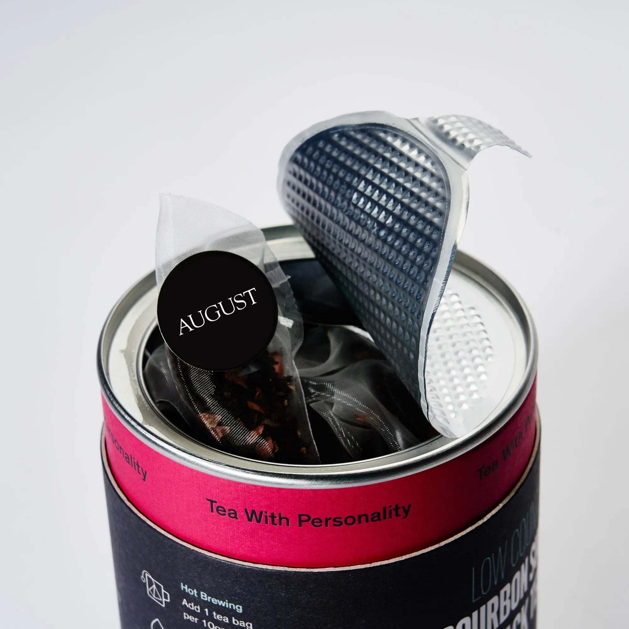 Low Country black tea in a navy and hot pink tin, with a pyramid tea bag and textured silver lid