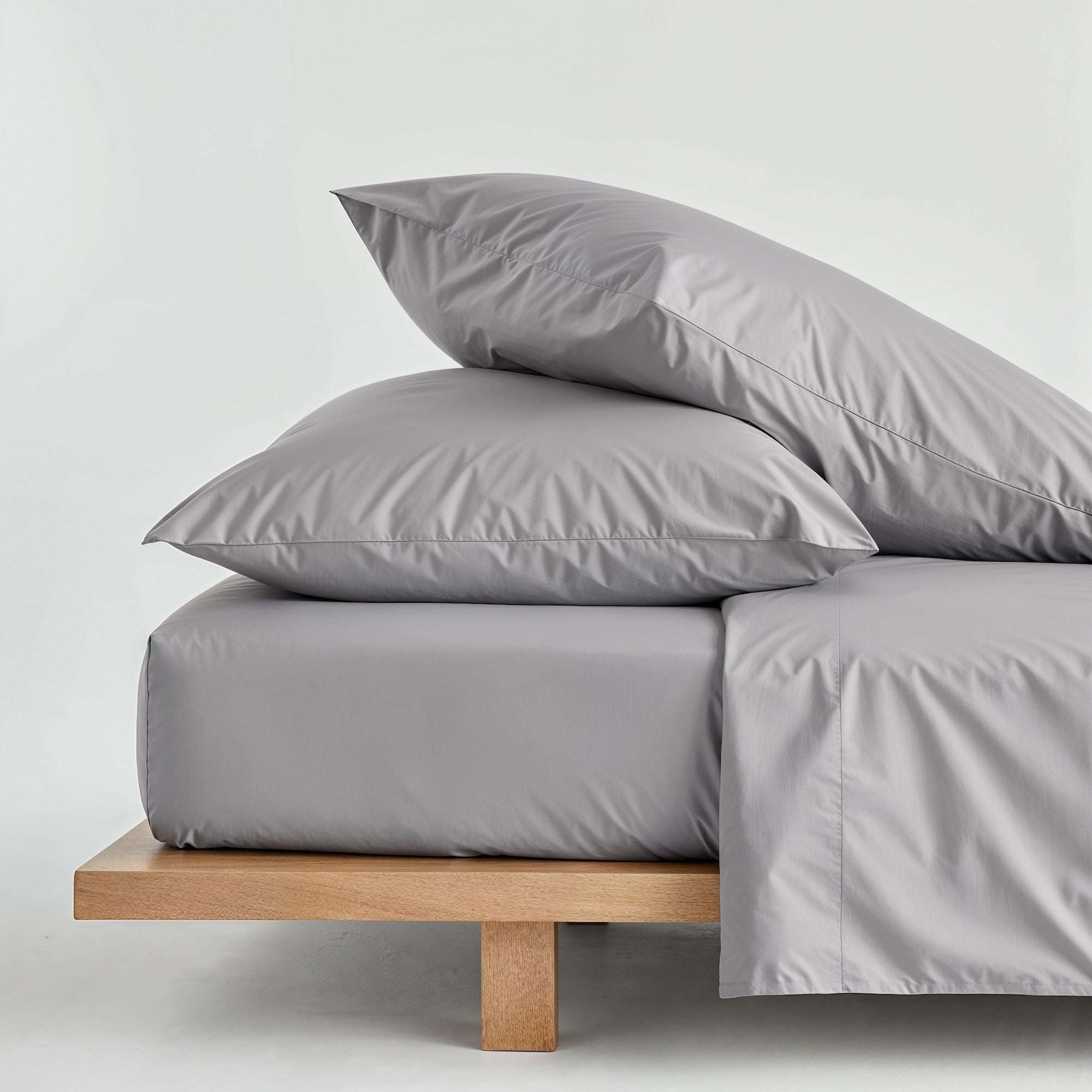 Luxe Australian Sateen Bedding in soft gray cotton, with smooth sheets, a draped duvet cover and stacked pillows