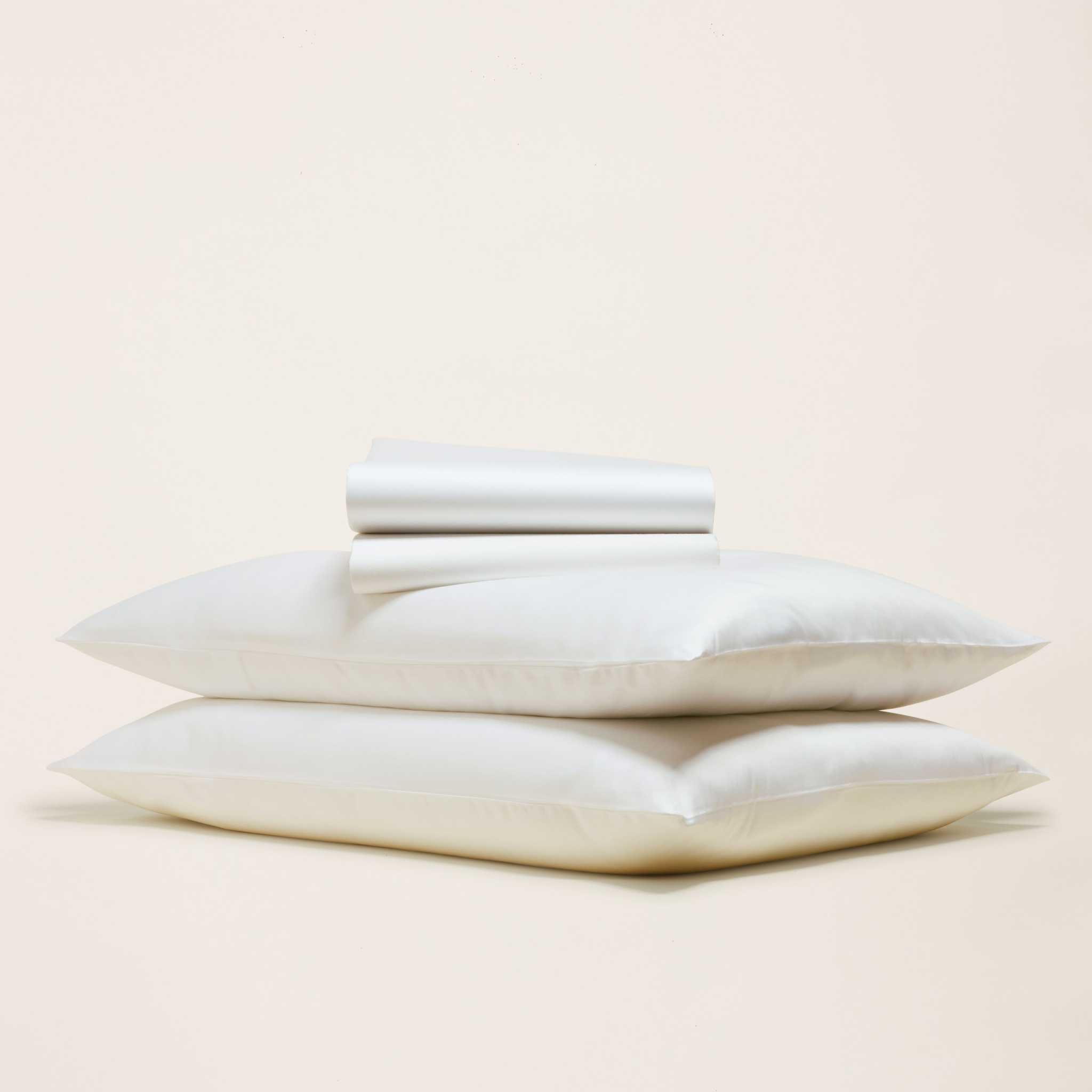 Luxe Australian Sateen Sheet Set in crisp white cotton sateen, folded fabric resting on two plump pillowcases